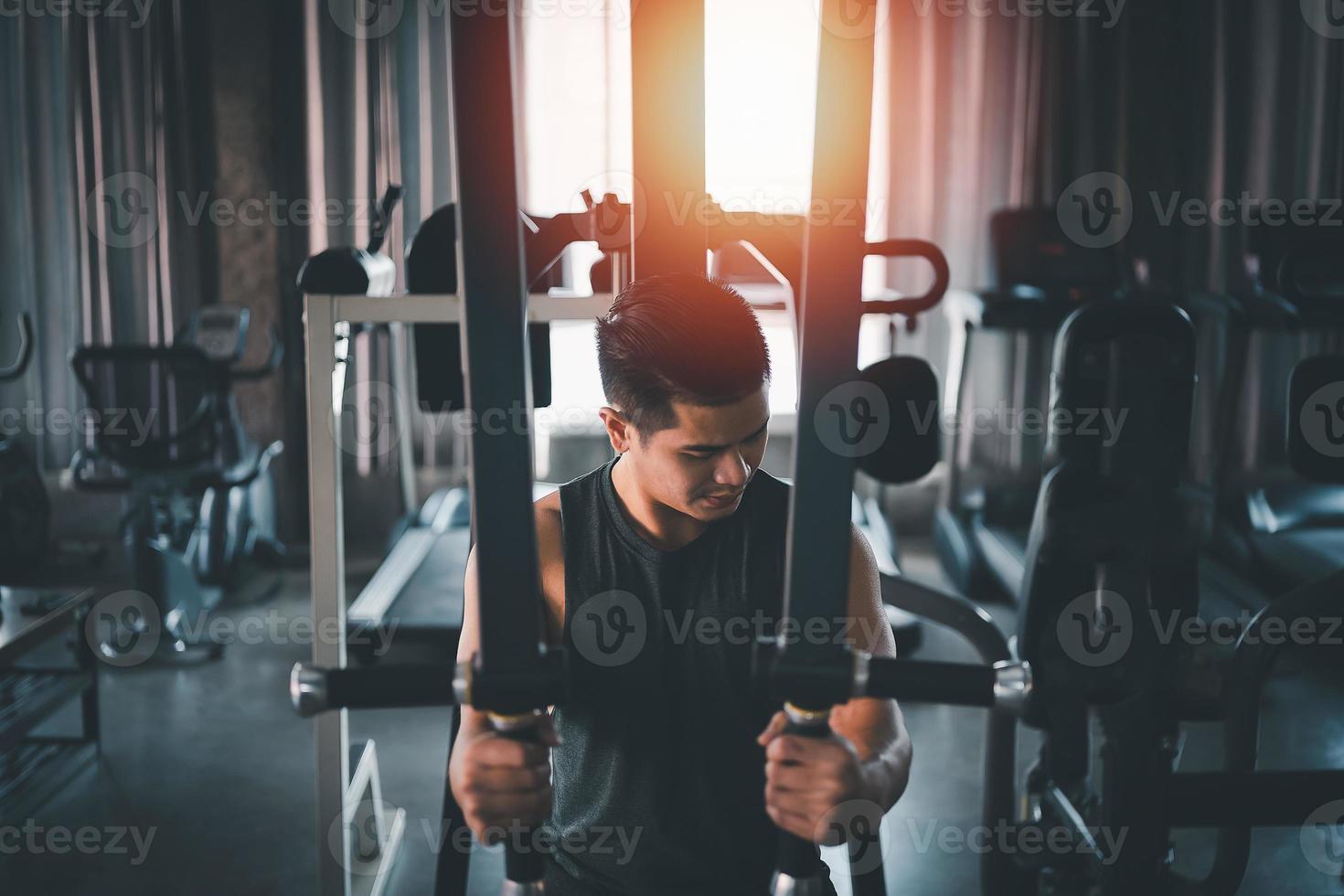 uomo sportivo che usa l'esercizio della macchina sportiva in palestra. body building asiatico per l'allenamento muscolare. concetto di palestra per la salute sportiva foto