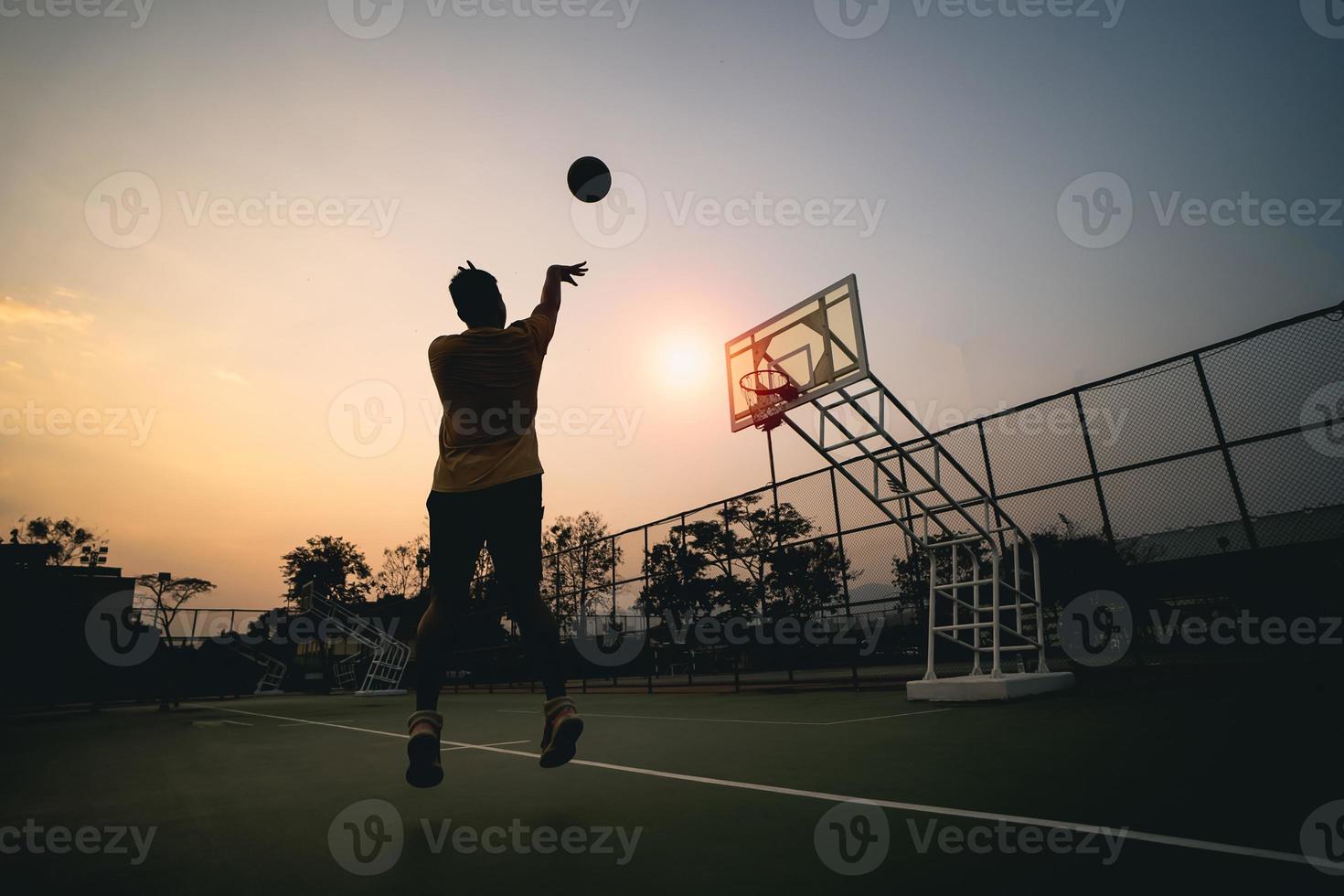 sagoma del giocatore di basket al tramonto. giocatore di basket spara un colpo. concetto di basket sportivo. foto