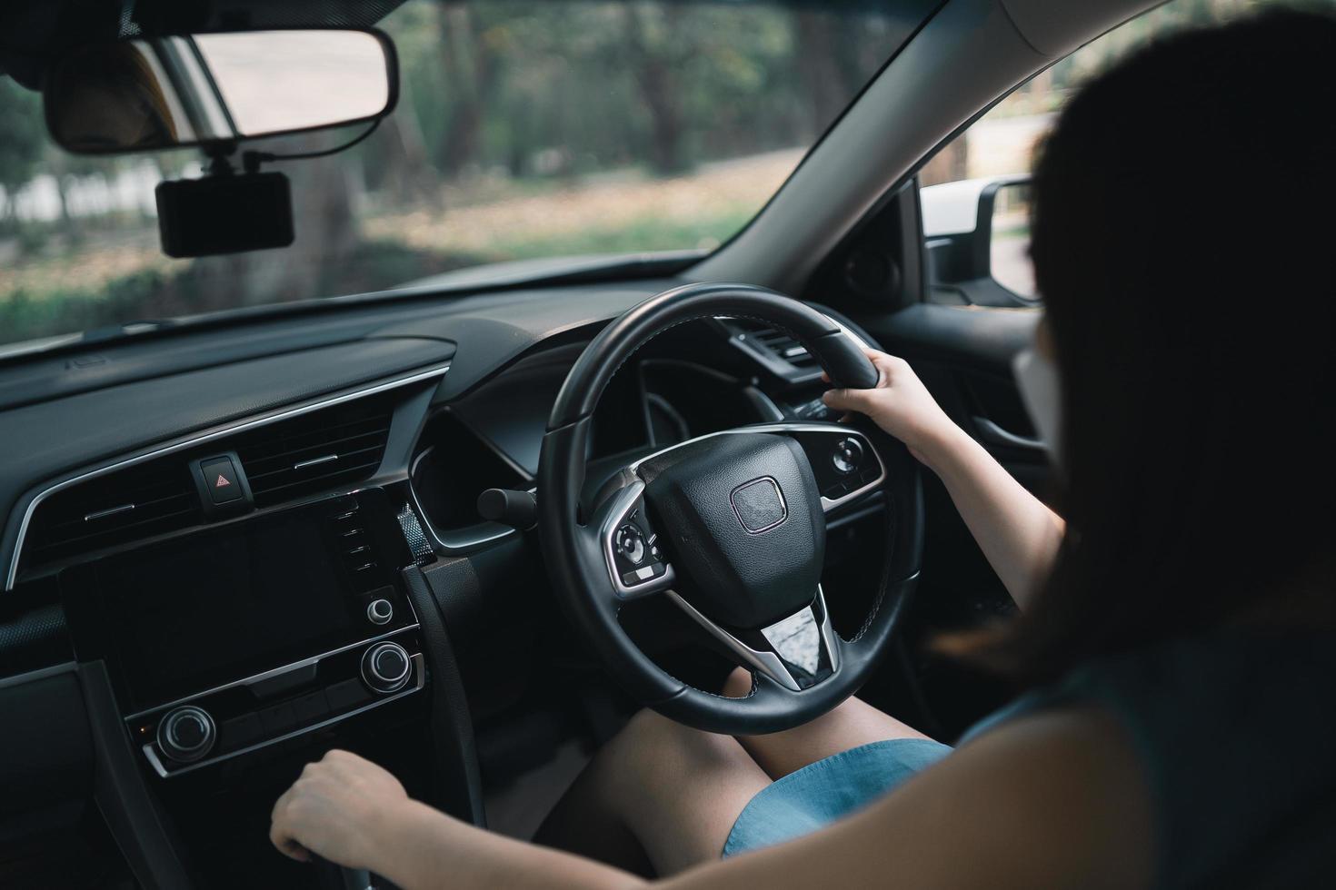 donna asiatica che indossa una maschera chirurgica durante la guida dell'auto. durante la pandemia di covid-19 indossare una maschera quando guidi l'auto esci fuori casa. foto