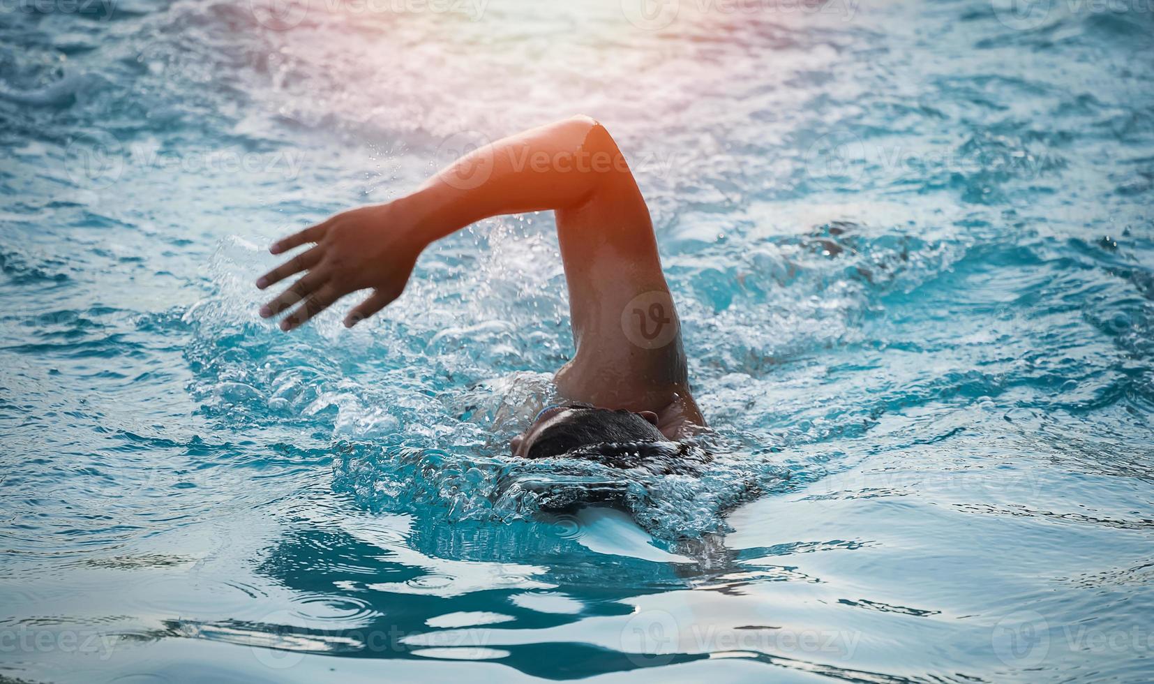 sport uomo nuotatore triathlon fitness atleta formazione nuoto nella piscina a onde in palestra centro benessere. nuotatore uomo che nuota nel panorama della bandiera dell'acqua blu. sport e fitness cardio esercizio. foto