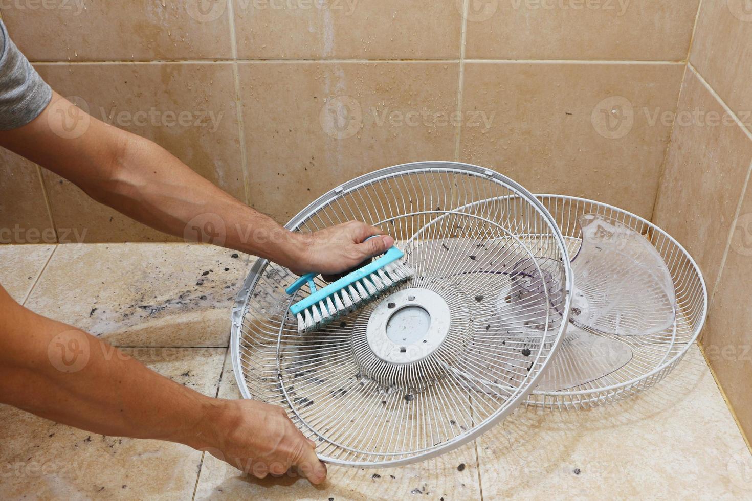 primo piano di un uomo che pulisce le parti di un ventilatore. foto