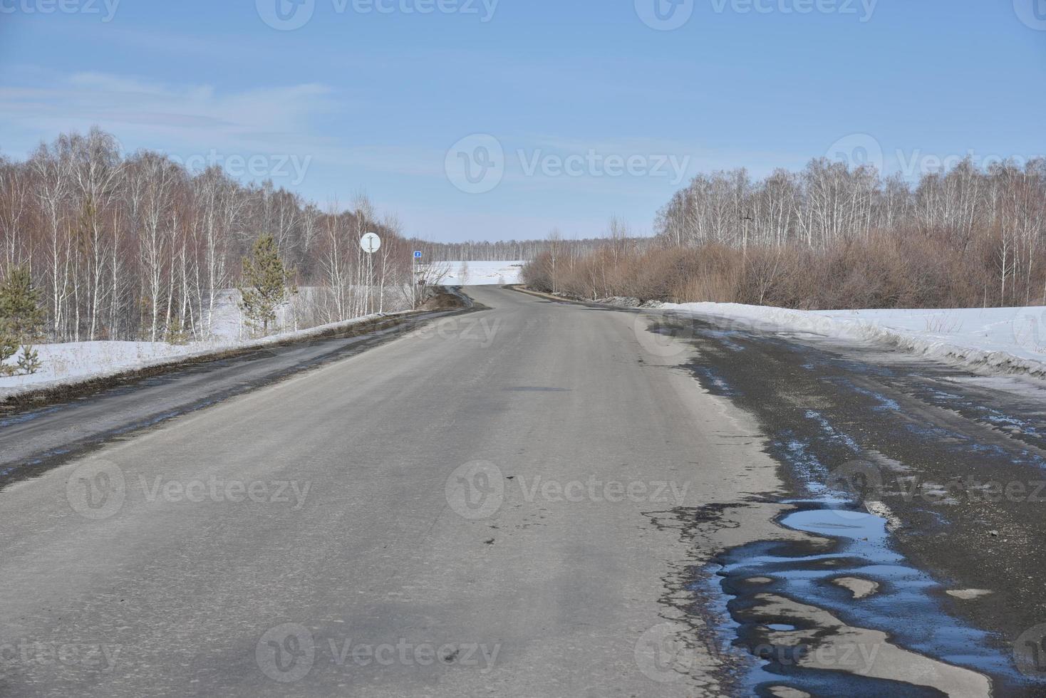 autostrada nel pomeriggio di primavera con pozzanghere e neve foto