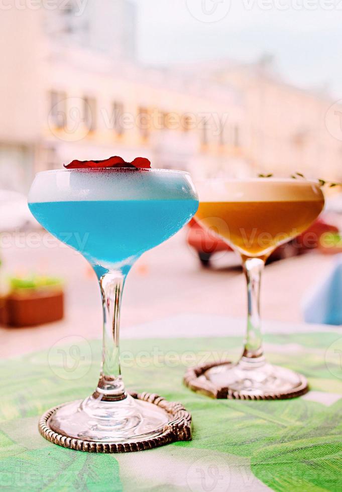 blu curacao e cocktail beige in piedi sul tavolo all'aperto foto