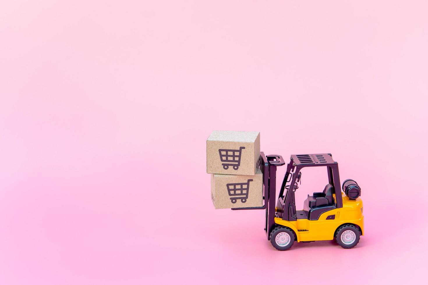 logistica e servizio di consegna - modello di carrello elevatore e cartoni di carta o pacchi con logo carrello su sfondo rosa. servizio di spesa sul web online e offre consegna a domicilio. foto