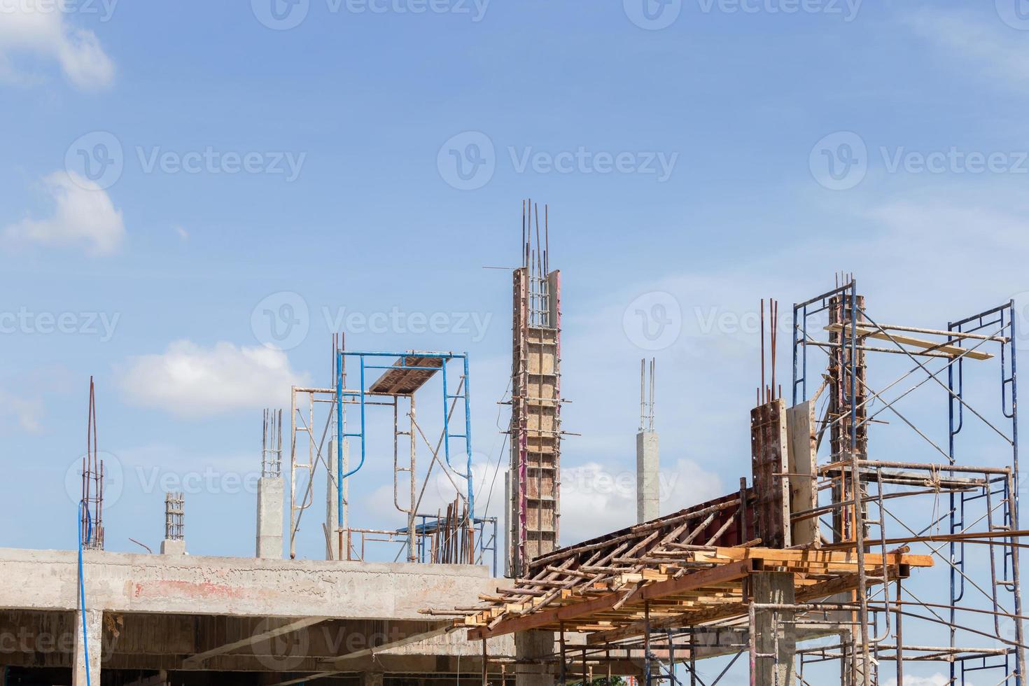 Costruzione e cantiere in corso, cassaforma a trave fabbricata da un operaio edile, pilastro e trave in costruzione in cantiere contro un cielo nuvoloso foto