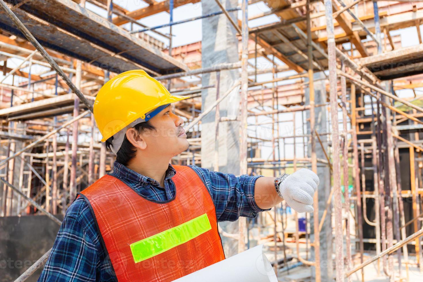 ingegnere caposquadra che controlla e pianifica il progetto in cantiere, uomo che tiene il progetto con sfondo sfocato foto