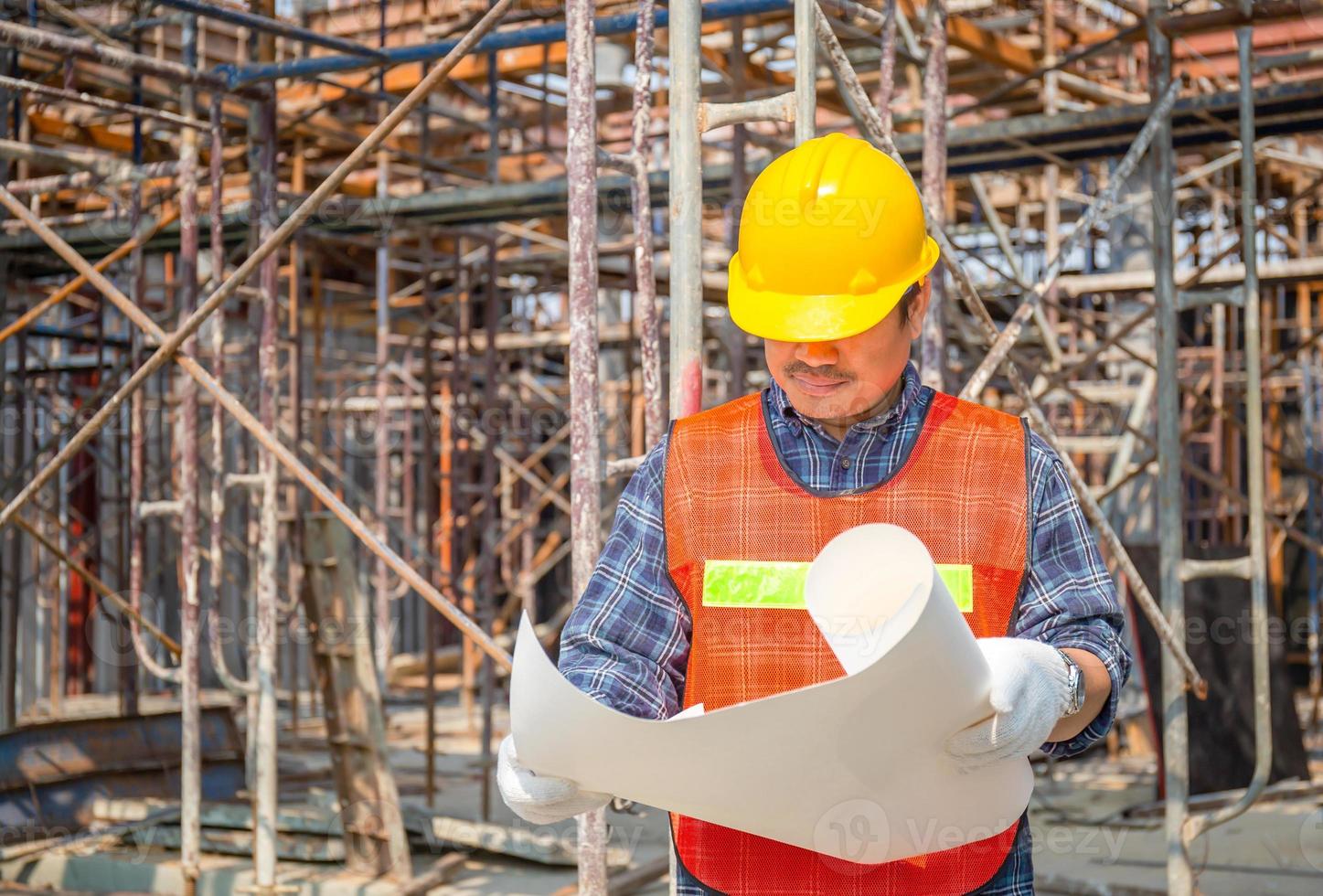 uomo lavoratore in elmetto che tiene il progetto di controllo e pianificazione del progetto in cantiere foto