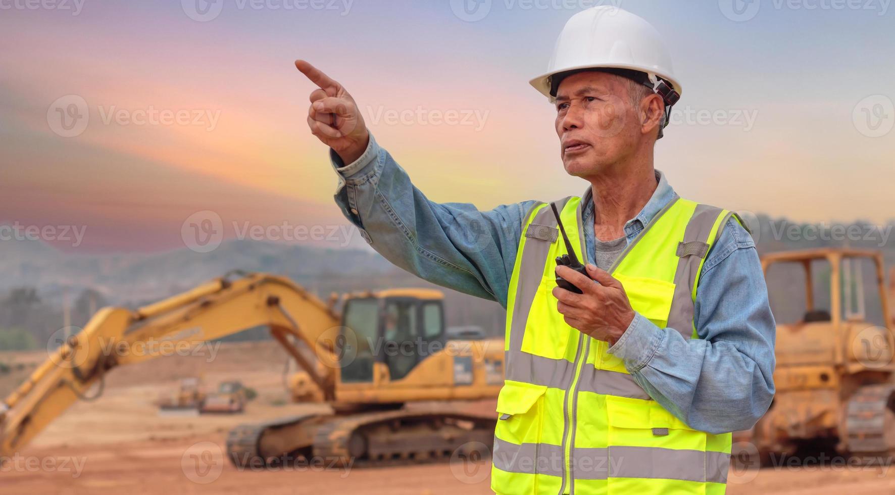 un ingegnere di mezza età usa un walkie-talkie sul posto di lavoro, un anziano asiatico supervisiona il lavoro serale. foto