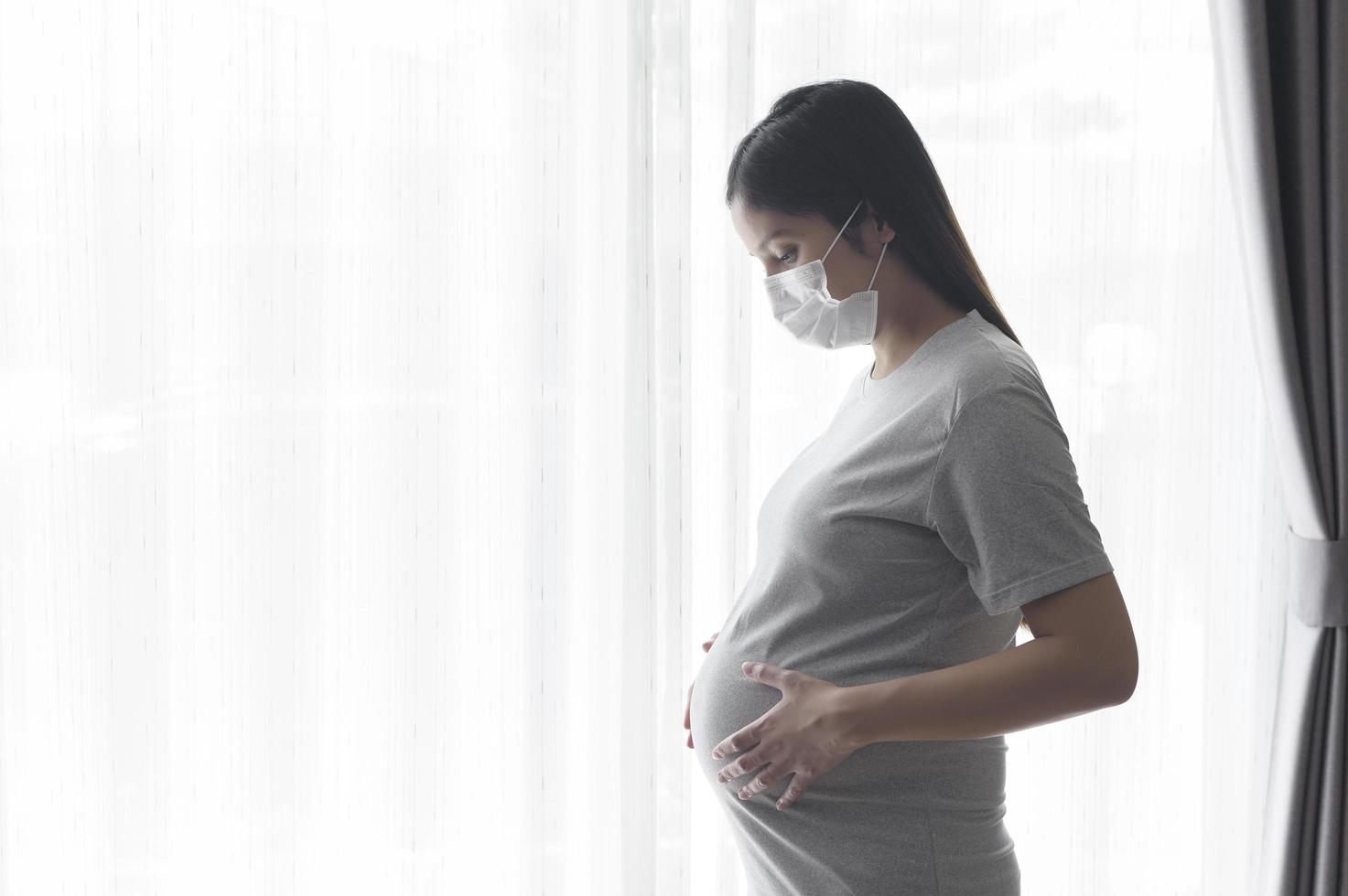 giovane donna incinta che indossa una maschera protettiva e si aspetta un concetto di bambino, sano e maternità foto