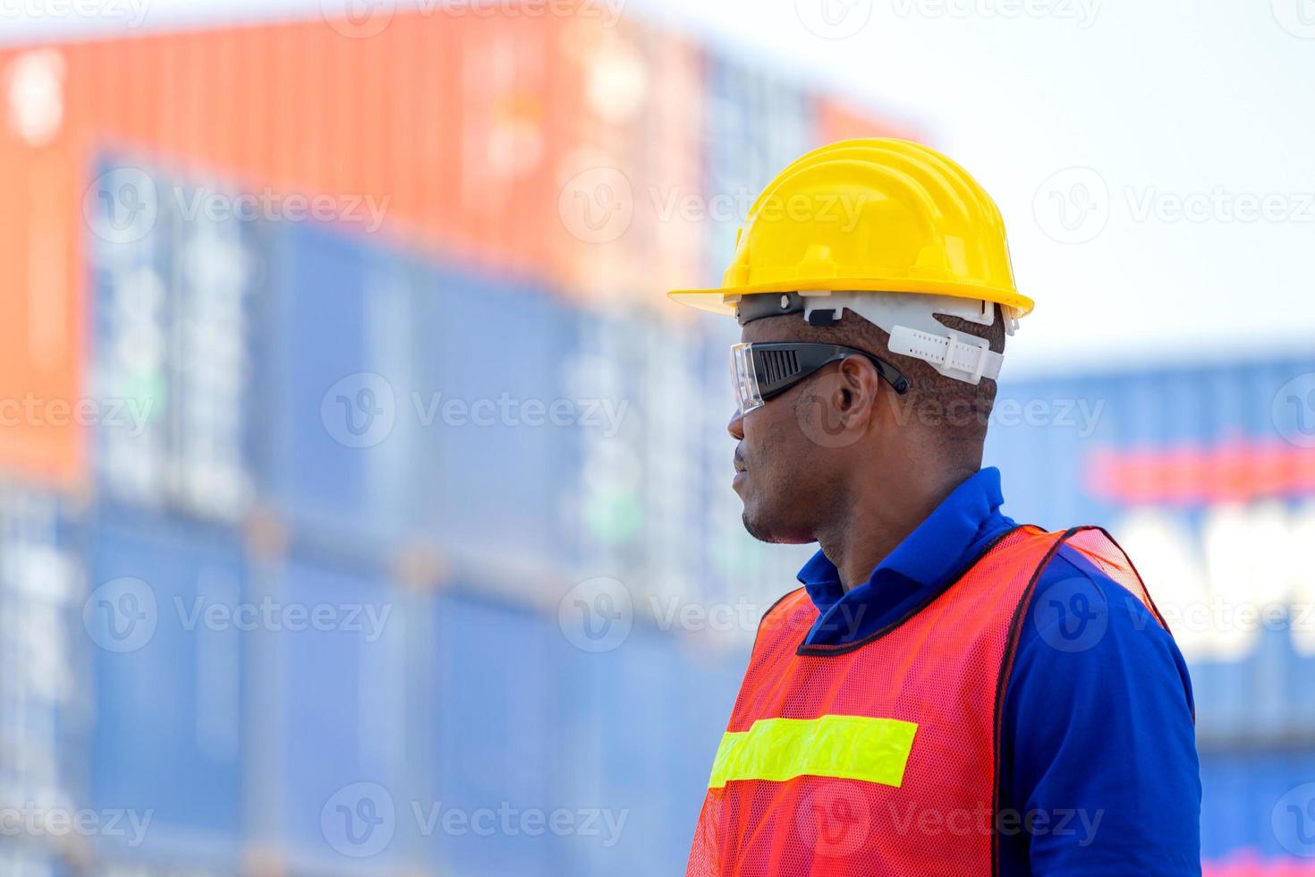 lavoratore in elmetto protettivo e giubbotto di sicurezza in piedi al carico di container, controllo del caposquadra che carica la scatola dei container dal carico foto