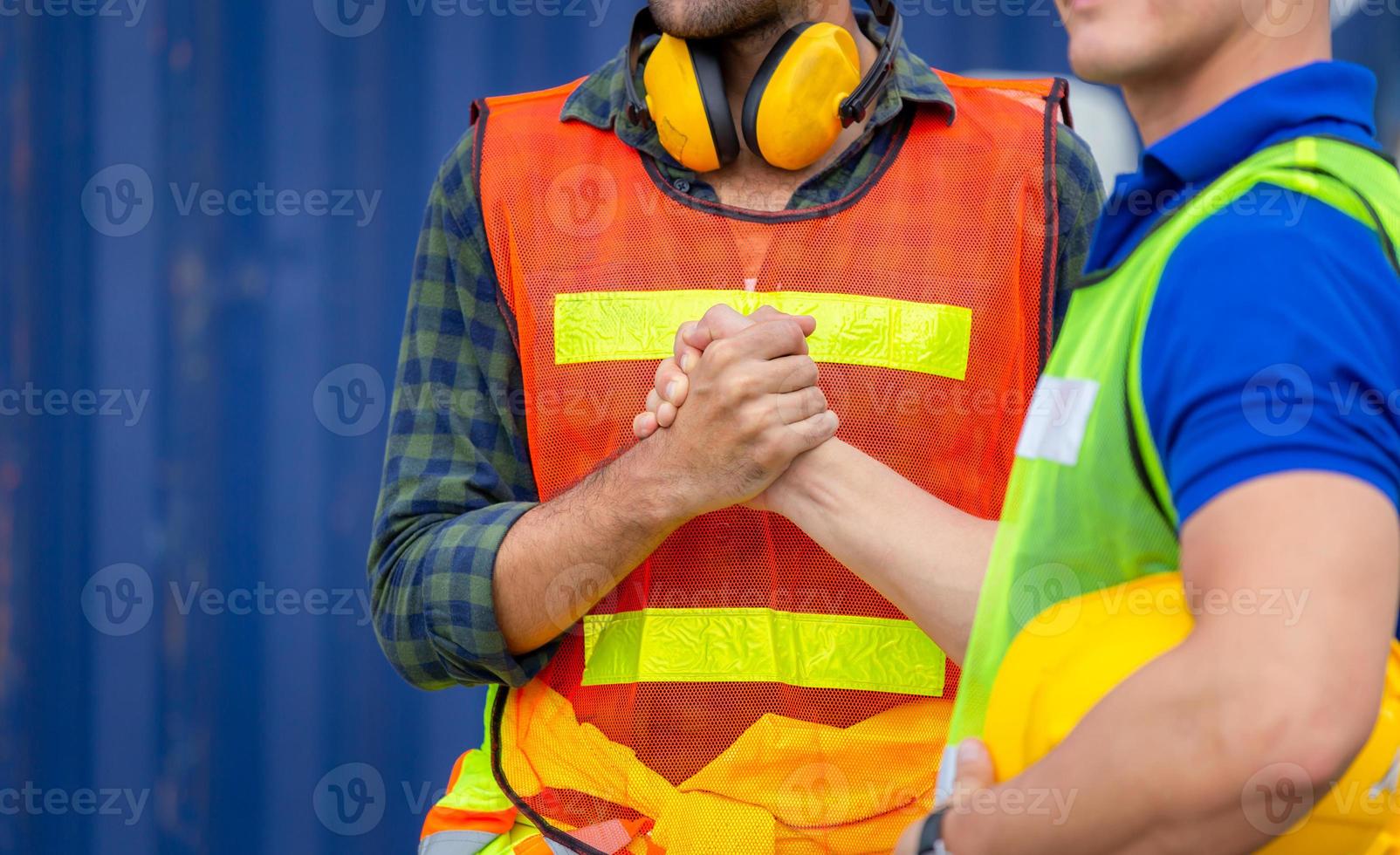 ingegnere e anima del lavoratore stretta di mano del fratello, stretta di mano della chiusura del pollice o stretta di mano dell'amico con sfondo del carico di contenitori sfocati, concetto di successo e lavoro di squadra foto