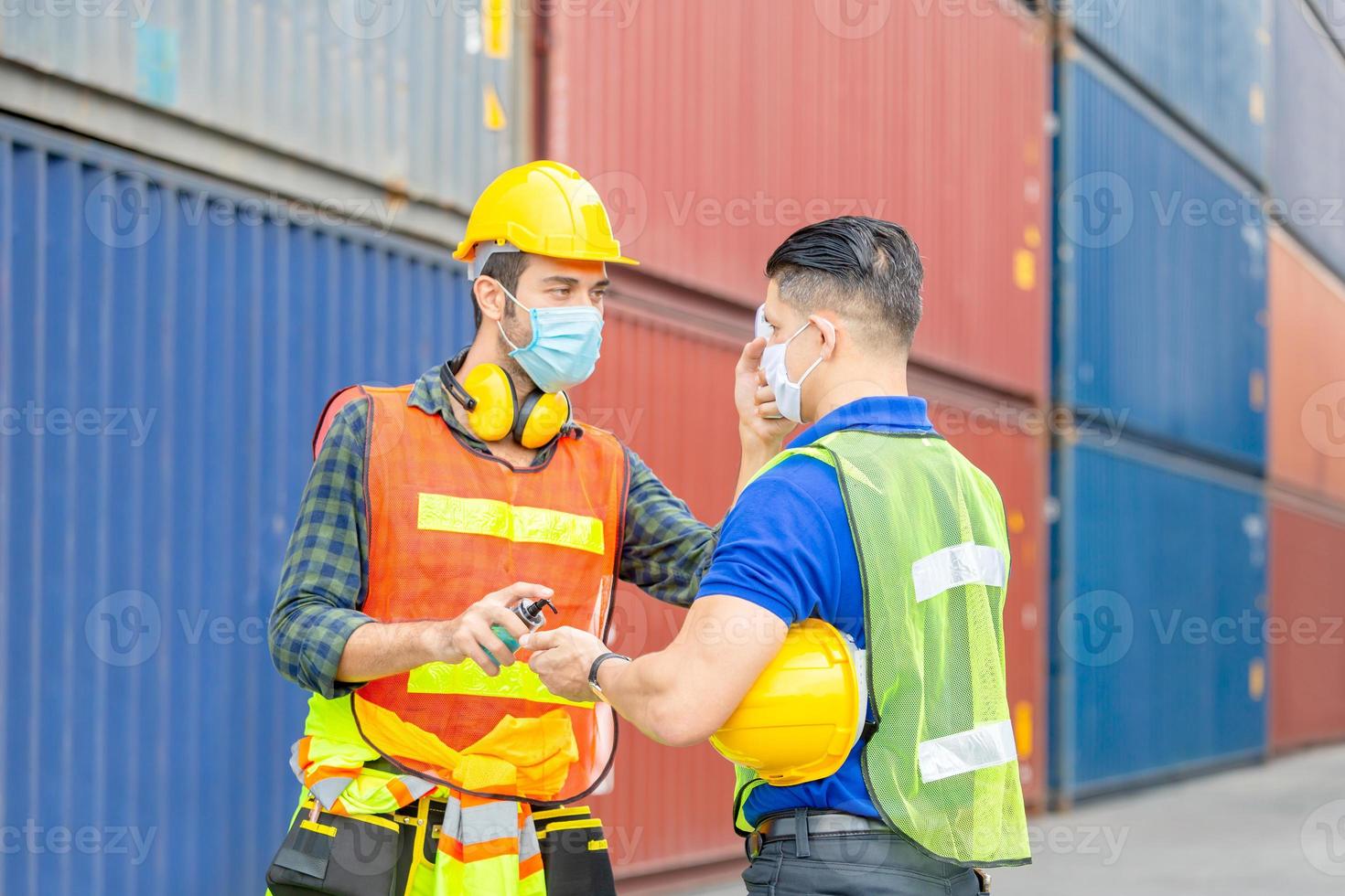 operaio di fabbrica che controlla la febbre con un termometro digitale per la scansione e la protezione dal coronavirus covid 19 nei container - concetto di assistenza sanitaria foto