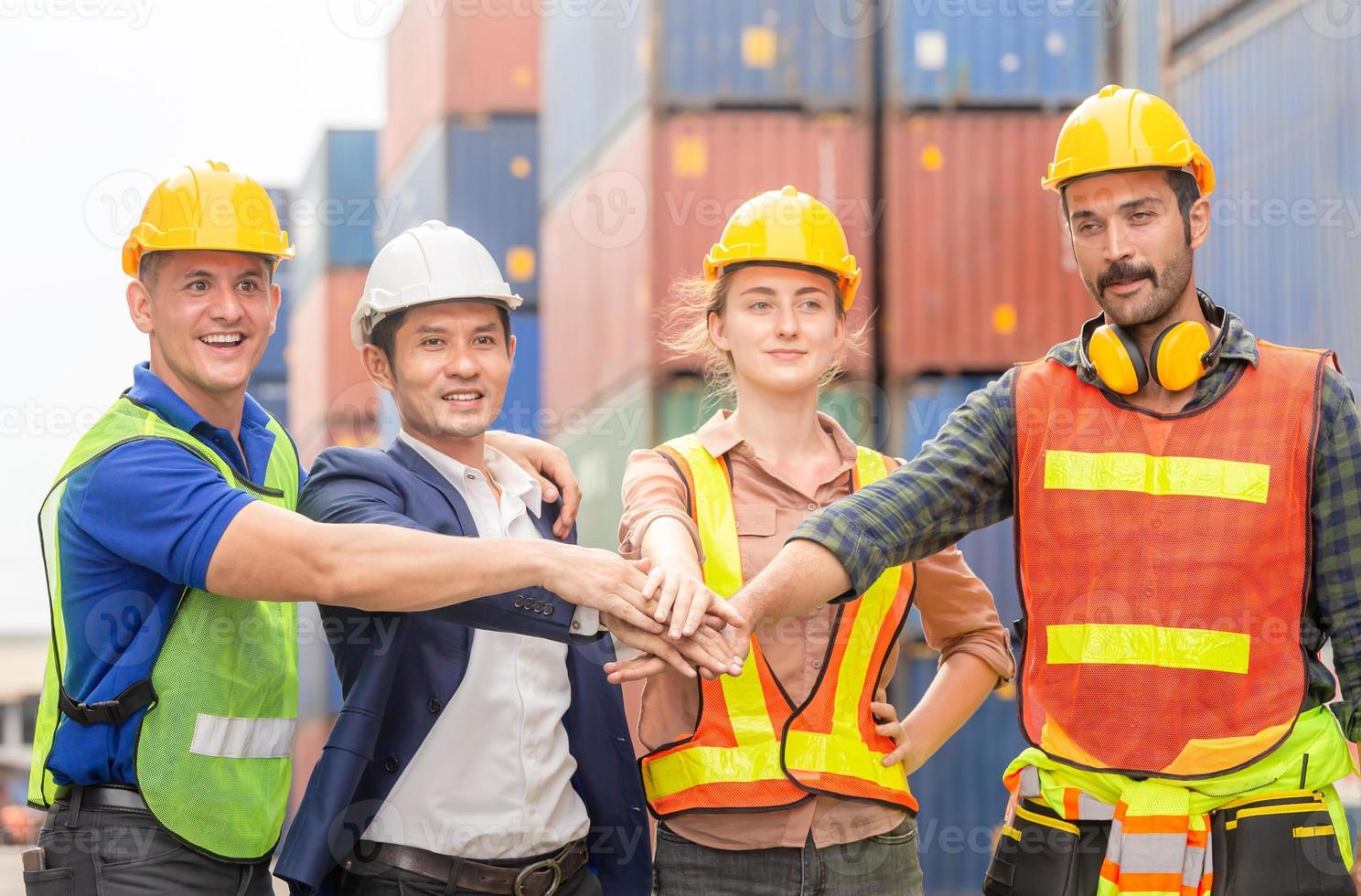 ingegnere della felicità e gruppo di lavoratori che uniscono le mani ai container. concetti di lavoro di squadra di successo foto