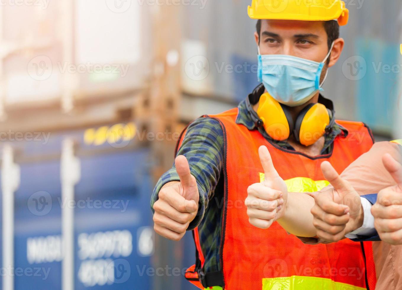 il team di ingegneri e lavoratori di uomini d'affari che indossa una maschera protettiva contro il coronavirus con il pollice in alto, il successo e il concetto di lavoro di squadra foto