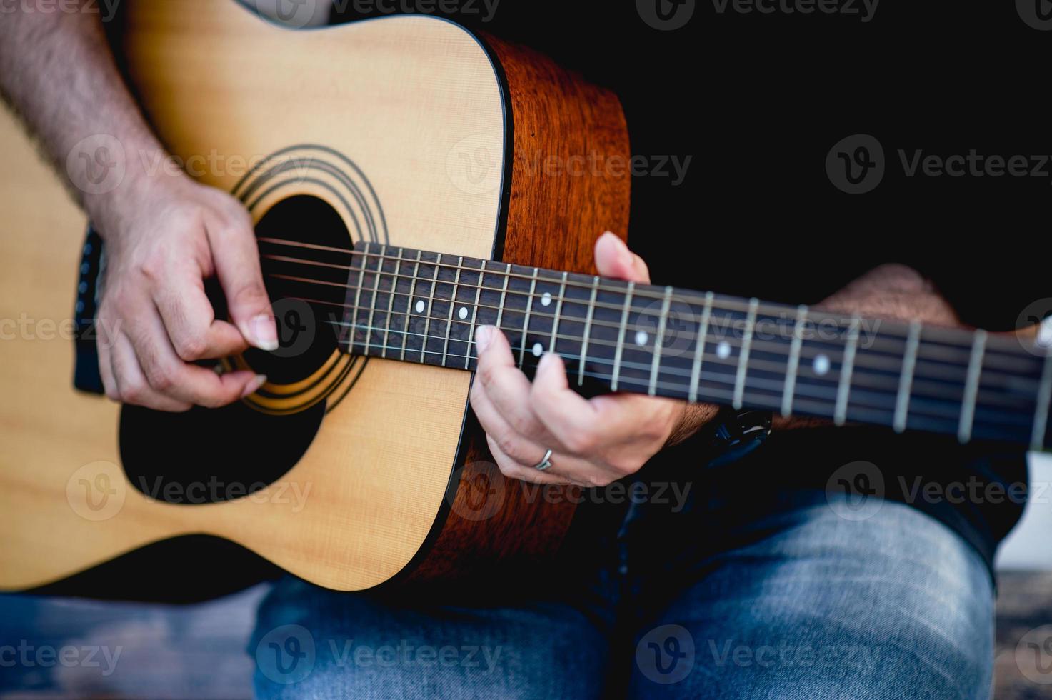 immagine di un chitarrista, un giovane che suona una chitarra mentre è seduto in un giardino naturale, concetto musicale foto