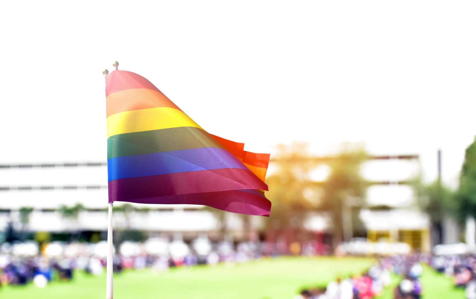 bandiera arcobaleno, un simbolo per la comunità lgbt, che sventola nel vento con sfocatura sullo sfondo delle attività mattutine degli studenti asiatici. concetto per sostenere e fare campagna per le comunità lgbt a scuola foto