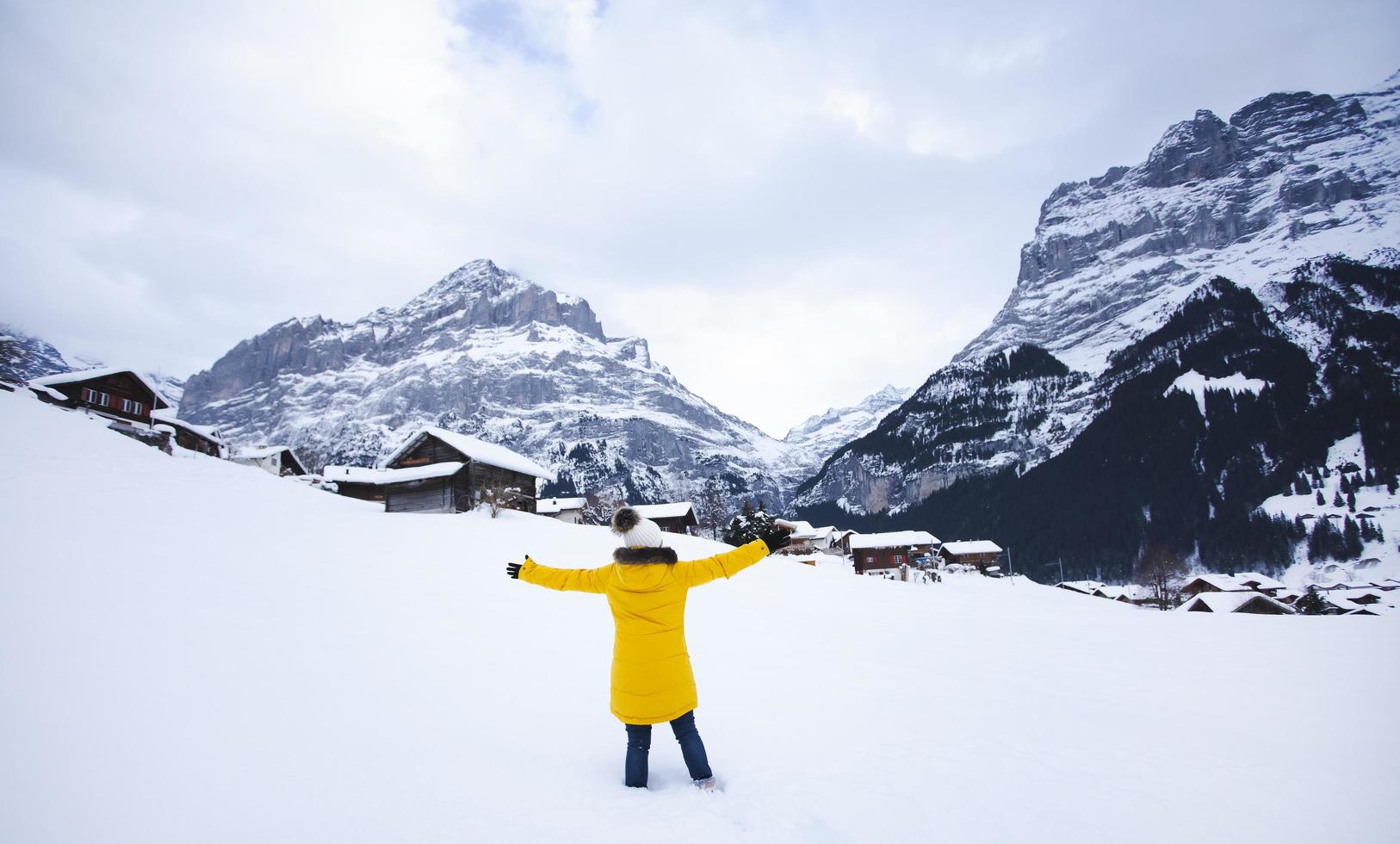 grindelwald svizzera cima d'europa, donna asiatica che indossa un cappotto giallo. usa lo smartphone scatta una foto montagna di neve nella sua vacanza in montagna, viaggio inverno nevoso sul monte a grindelwald.