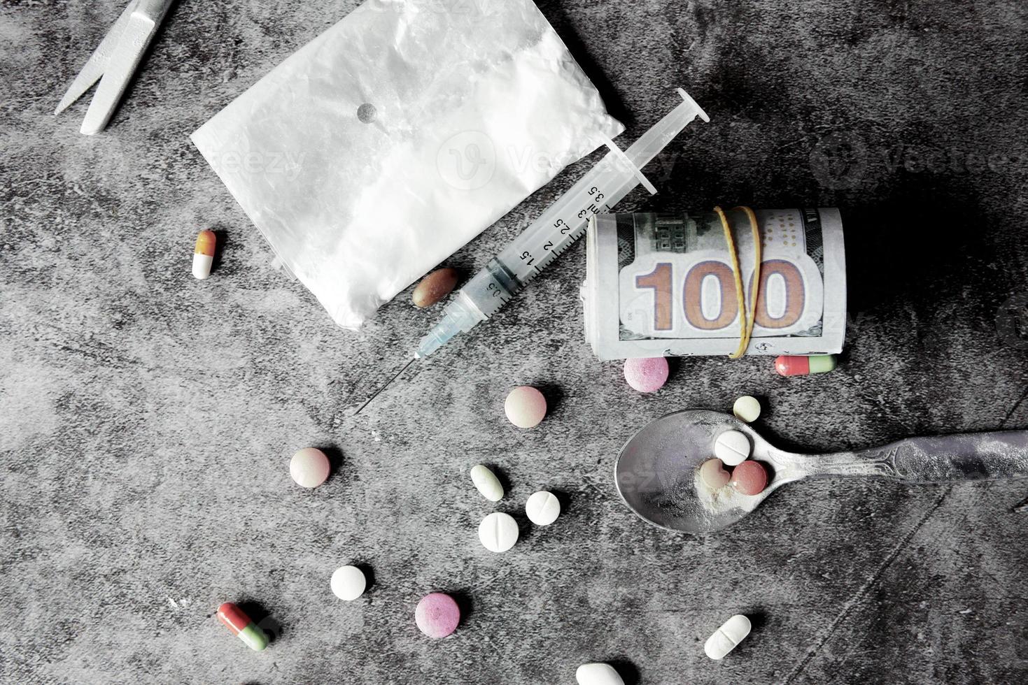 concetto di tossicodipendenza con pacchetto di eroina e siringa su sfondo nero foto