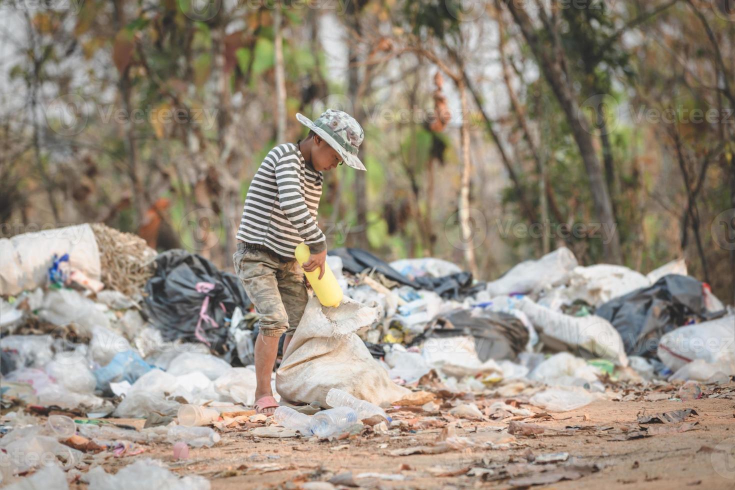 un povero ragazzo raccoglie immondizia da una discarica in periferia. vita e stile di vita dei poveri concetto di lavoro minorile, povertà, ambiente. raccolta differenziata. foto