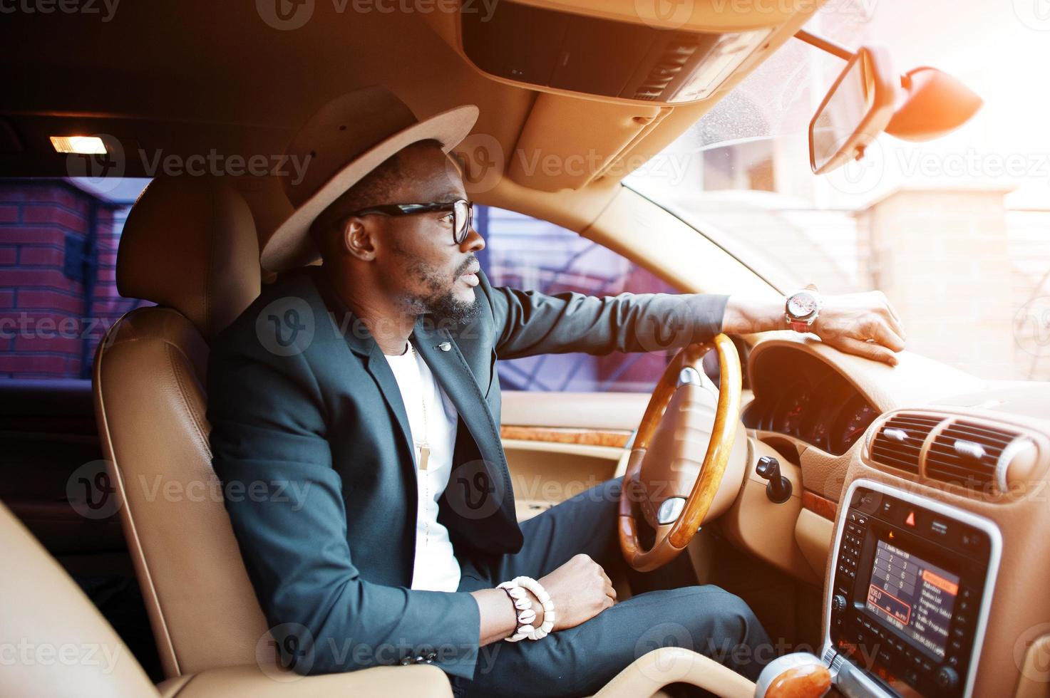 elegante uomo di colore seduto al volante di un'auto di lusso. ricco uomo d'affari afroamericano. foto