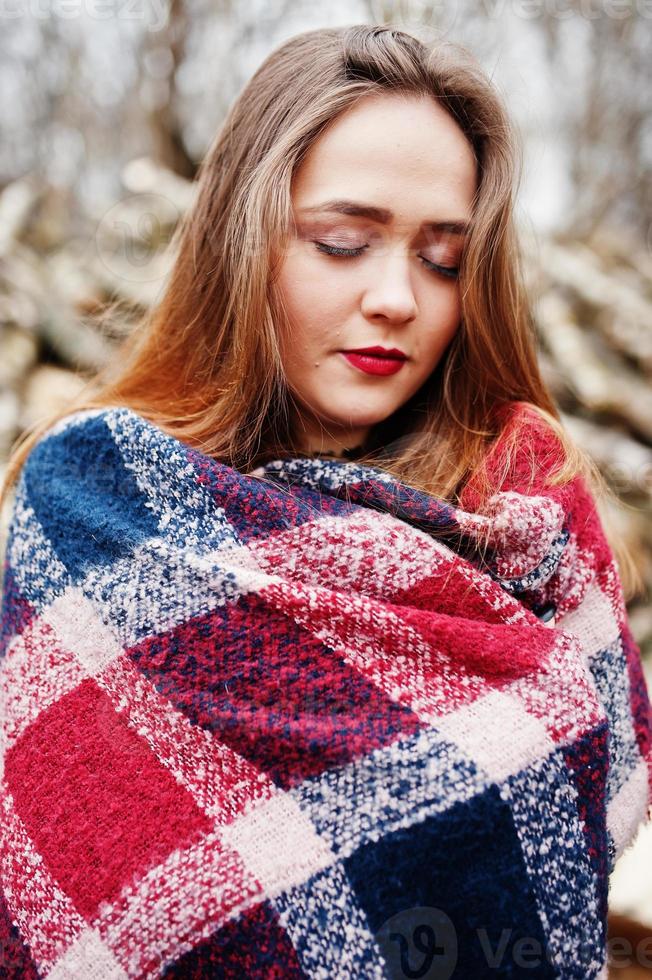 giovane ragazza hipster indossare su una coperta contro ceppi di legno su legno. foto