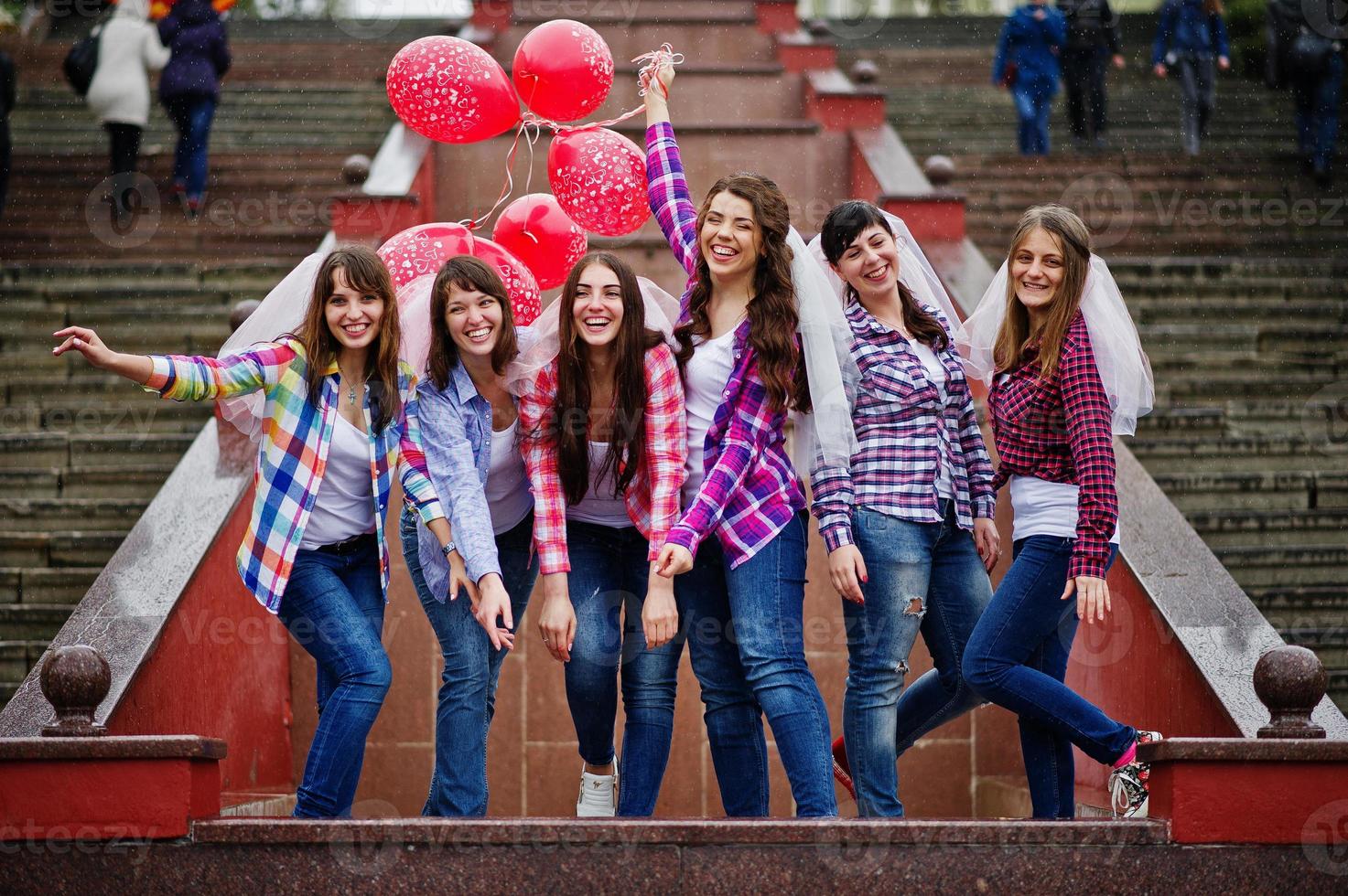 gruppo di sei ragazze che si divertono alla festa di addio al nubilato, con palloncini sotto la pioggia sulle scale della città. foto