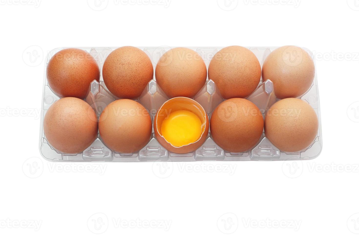 uova di pollo in vassoio di plastica isolato su sfondo bianco. un uovo è stato aperto per rivelare il tuorlo fresco all'interno. foto