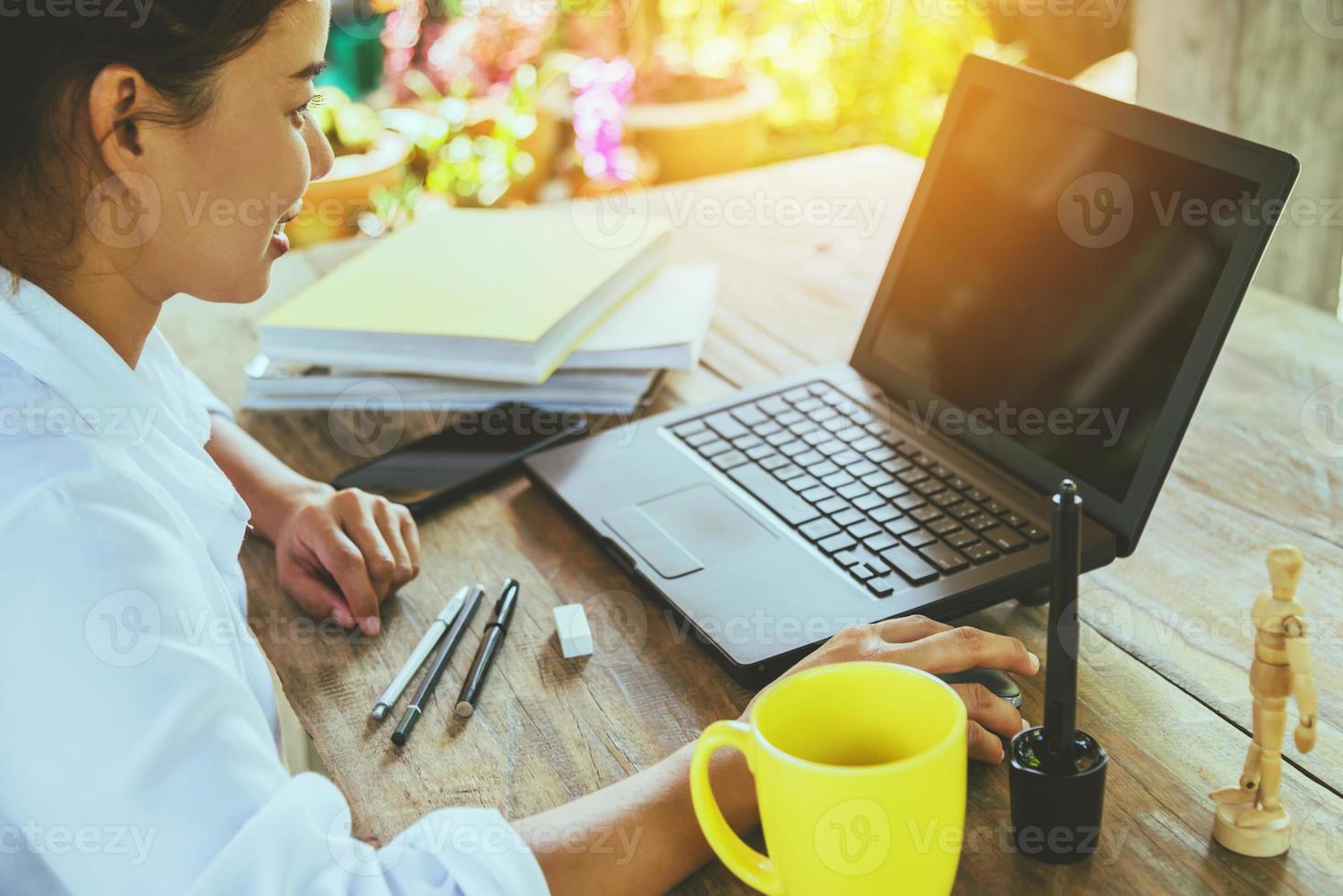 donne sedute a lavorare sul tavolo di legno che lavorano con un taccuino e bevono caffè a casa. in vacanza foto