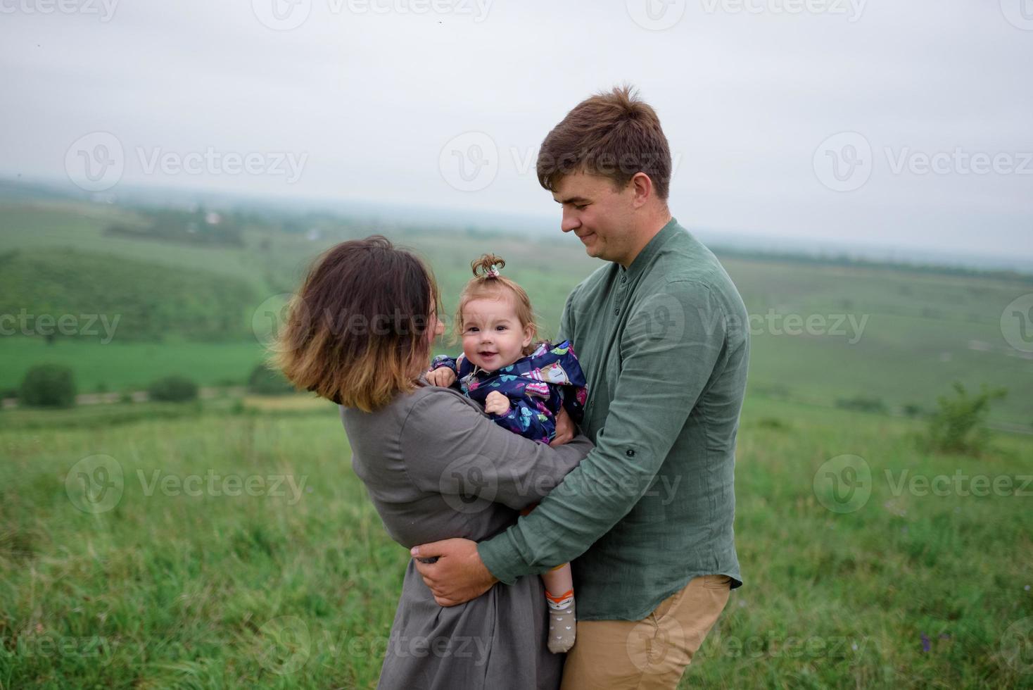 mamma, papà e figlia. i genitori tengono il bambino per mano e vanno verso la telecamera. foto