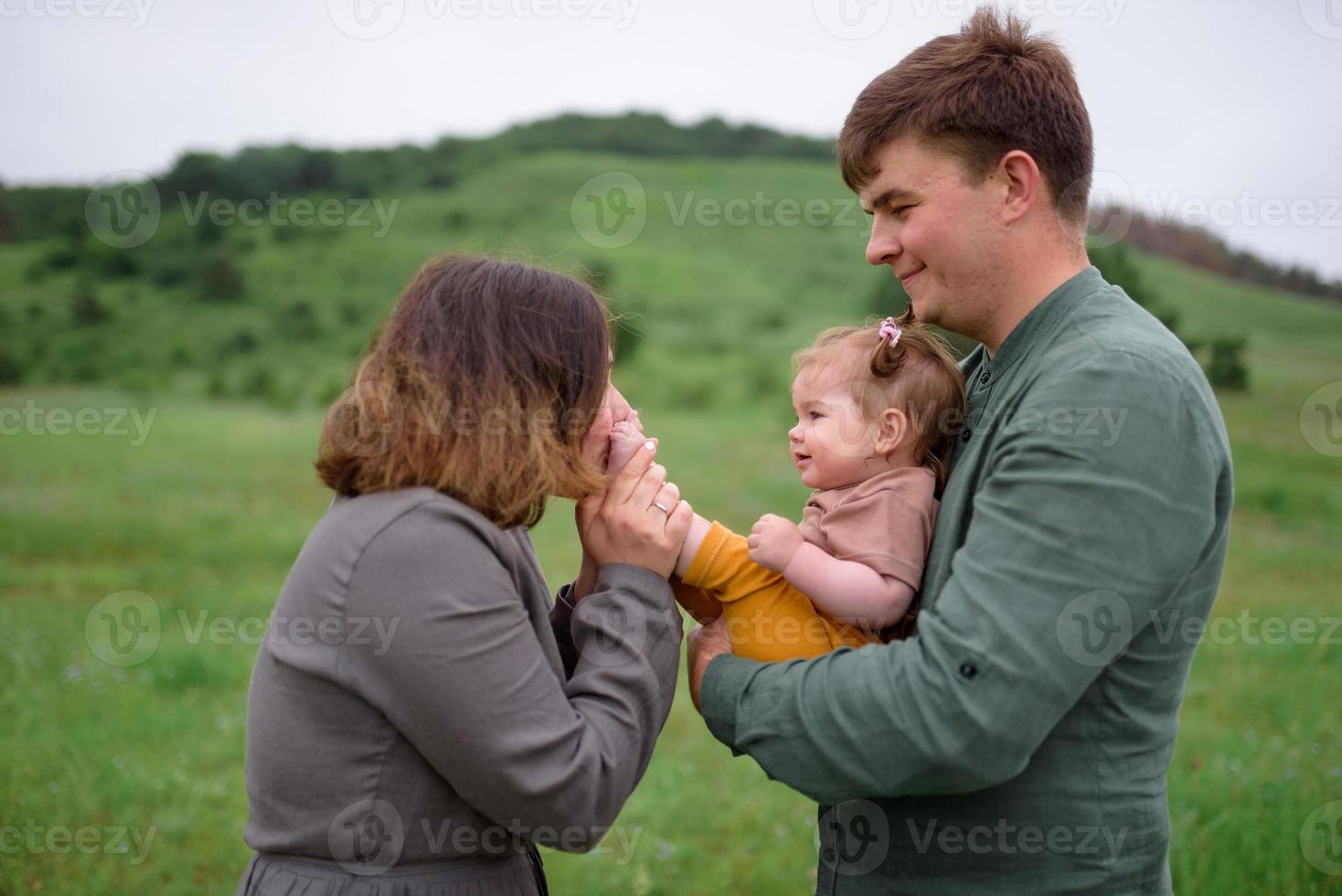 mamma, papà e figlia. i genitori tengono il bambino per mano e vanno verso la telecamera. foto