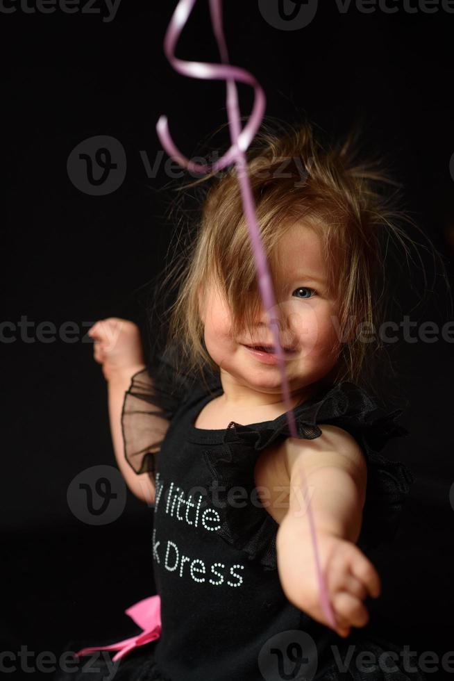 il giorno della festa di compleanno della bambina del primo anno. palloncini e vacanze al chiuso. compleanno del bambino. piccola bella ragazza nel suo primo vestito nero foto