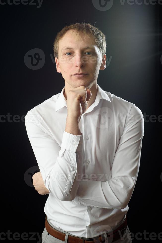 primo piano ritratto di un giovane uomo con una camicia bianca e cravatta nera, sorridente mentre guarda la telecamera, su sfondo chiaro dello studio foto