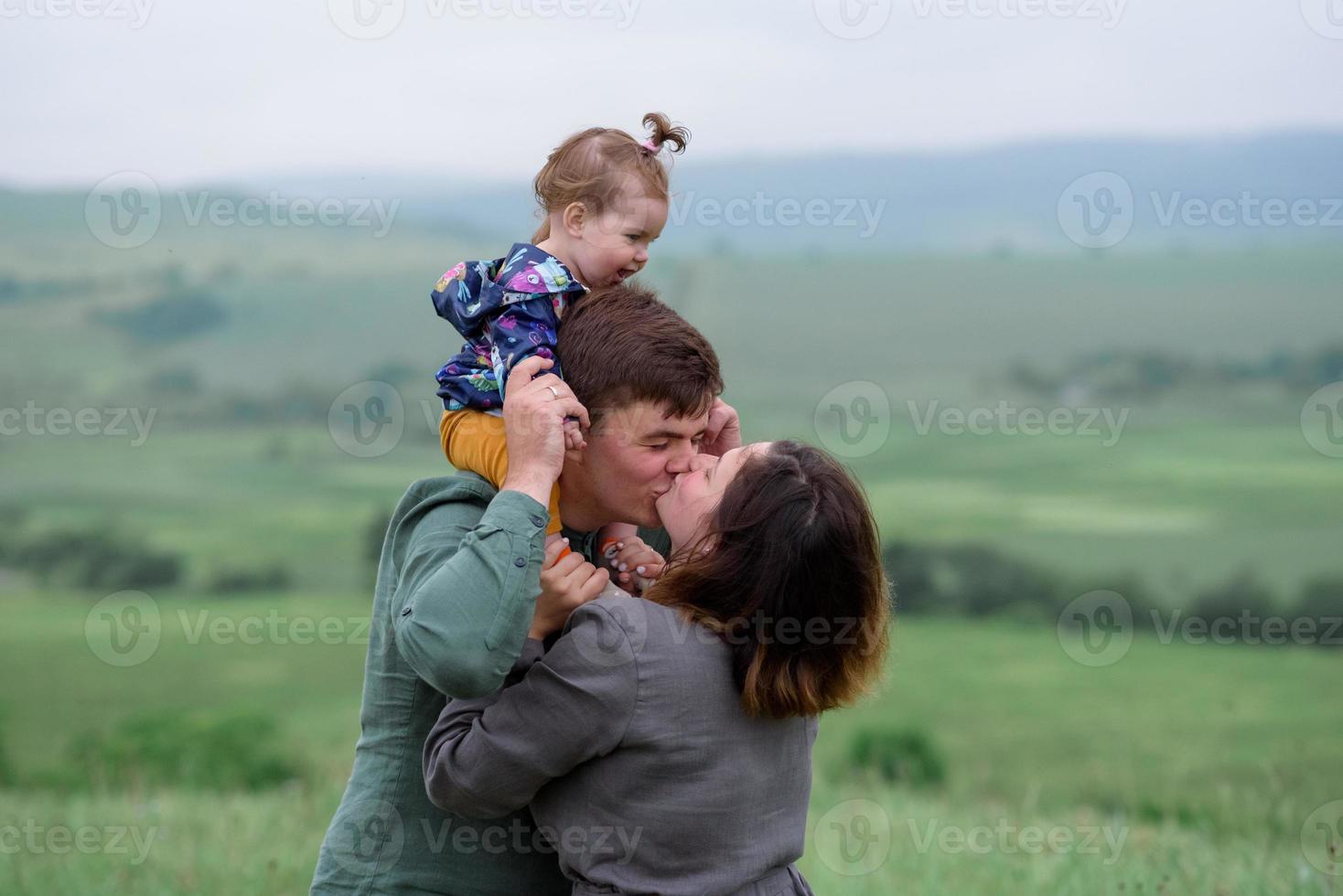 mamma, papà e figlia. i genitori tengono il bambino per mano e vanno verso la telecamera. foto