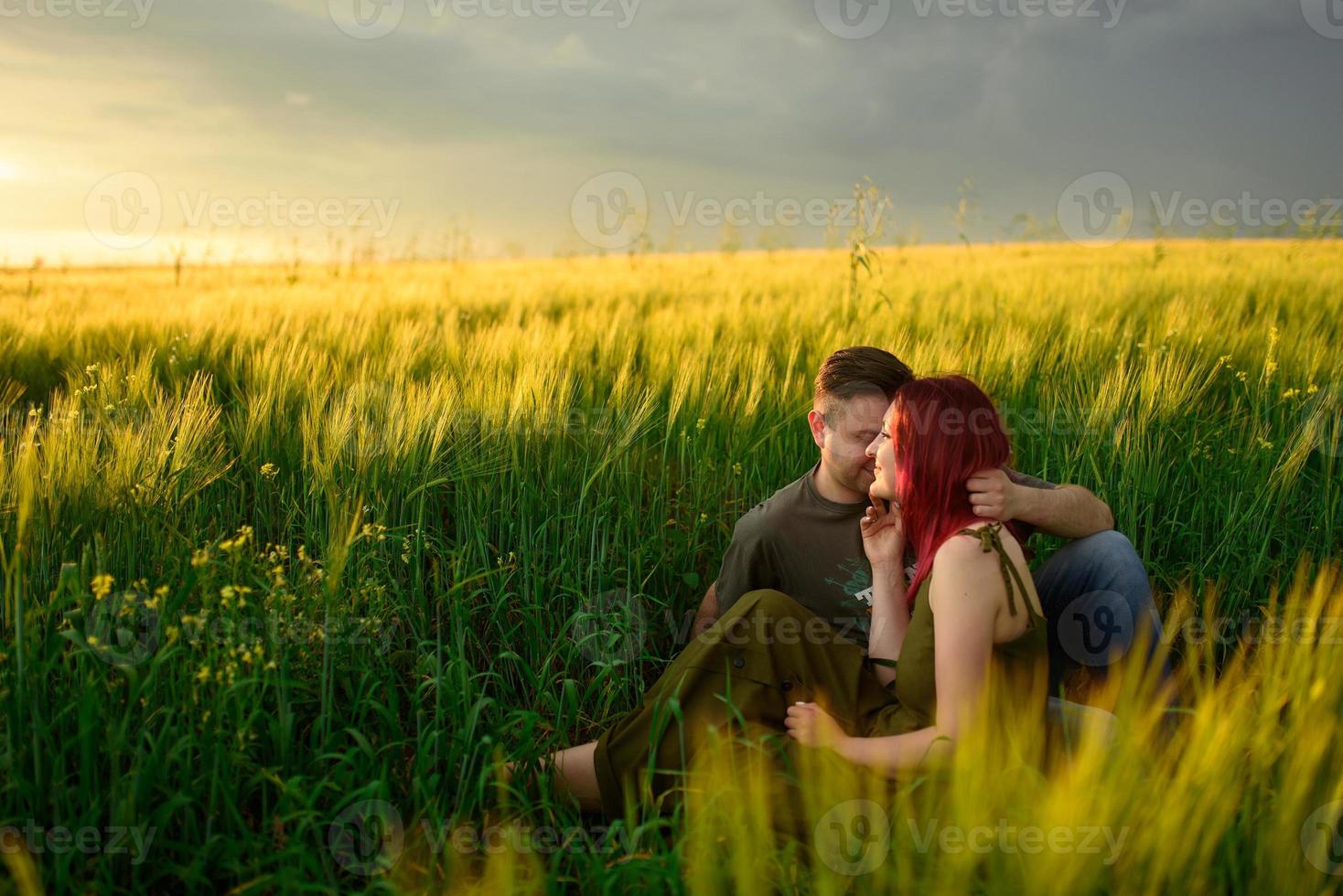 un uomo e una donna giacciono supini in un campo di grano. un uomo bacia una donna sulla guancia. la ragazza aprì la bocca con gioia. foto