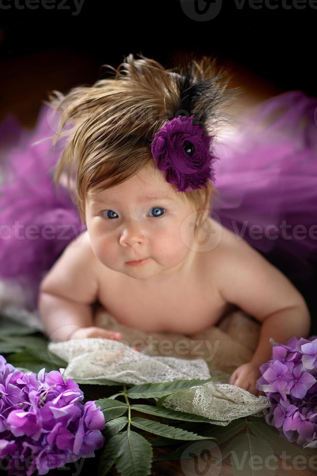 ritratto di una bambina carina. il bambino giace nei colori dell'ortensia viola foto
