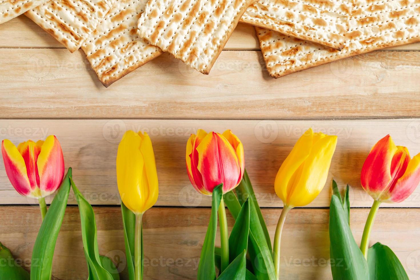 sfondo religioso festa ebraica pesach. tulipani e matzo su un tavolo di legno chiaro. foto