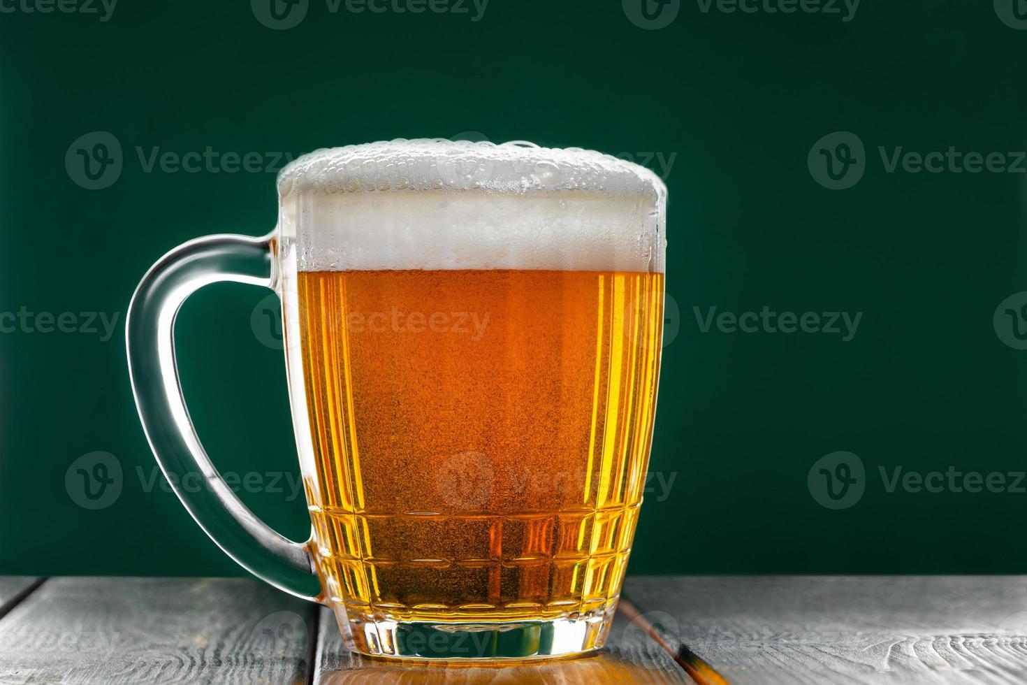 mug con la tradizionale birra chiara irlandese su sfondo verde scuro. foto