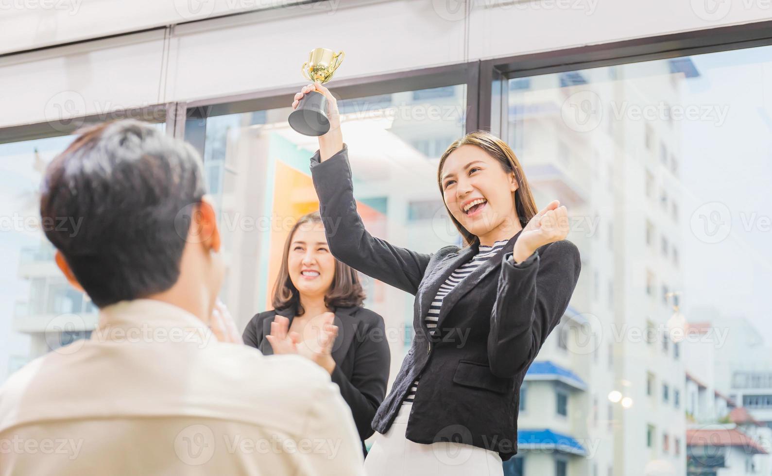 donna d'affari che tiene il trofeo del premio nella sala riunioni, concetto di squadra di felicità di successo di celebrazione foto