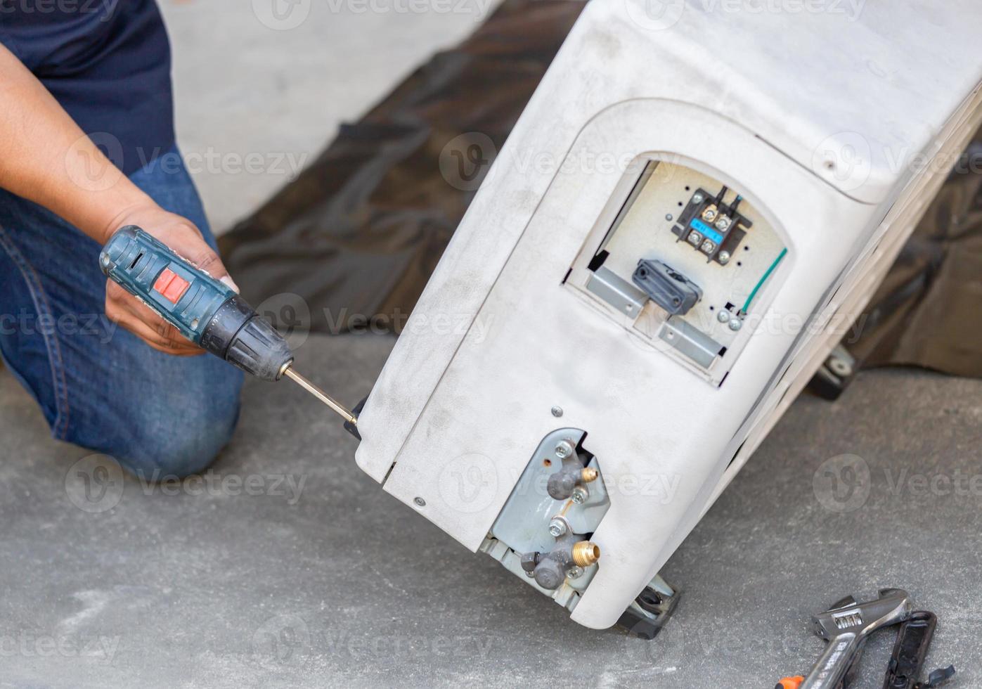 messa a fuoco selettiva riparazione dell'aria condizionata, mani dell'uomo tecnico utilizzando un cacciavite che fissa un moderno sistema di climatizzazione foto