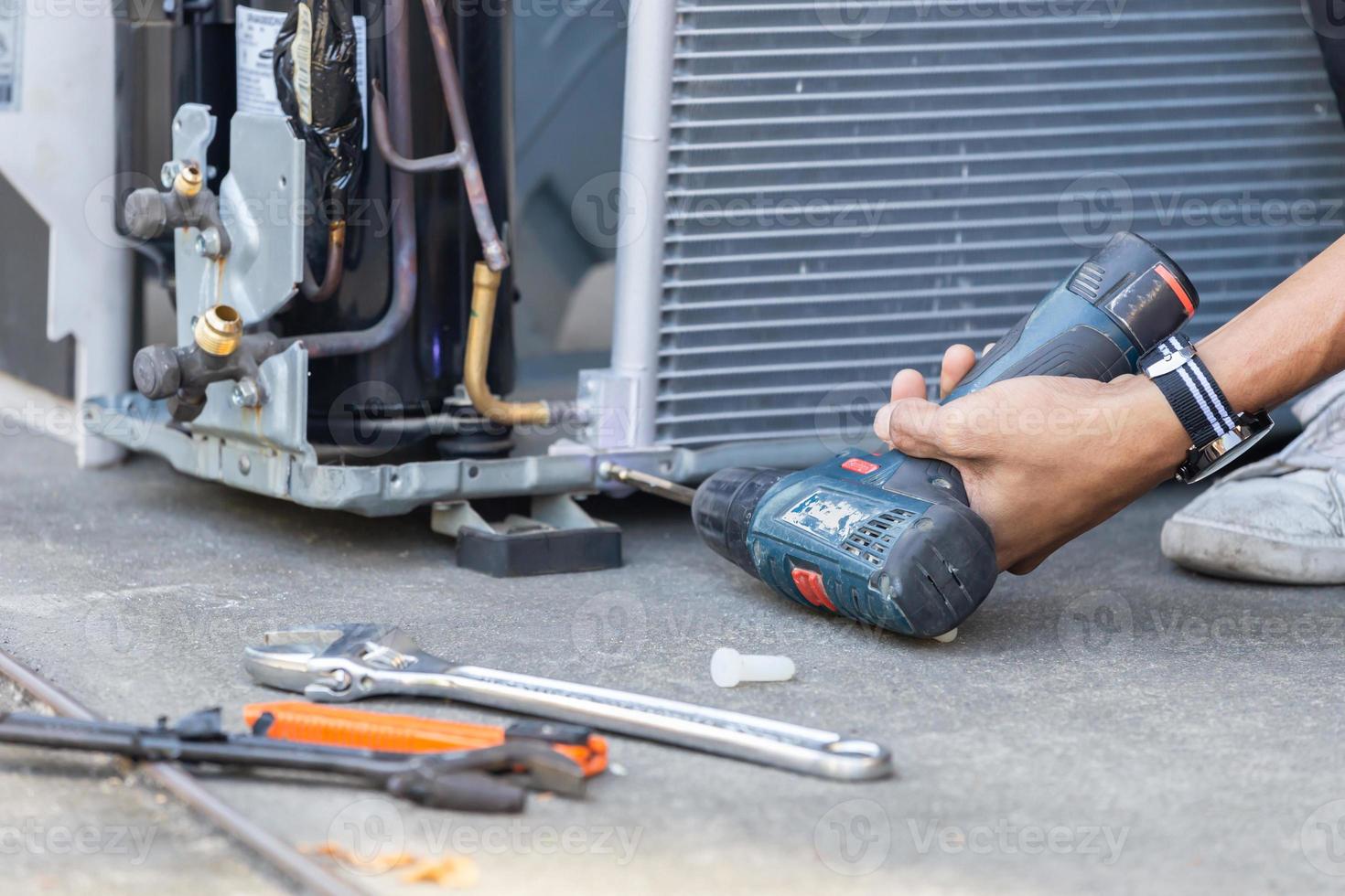 messa a fuoco selettiva riparazione dell'aria condizionata, mani dell'uomo tecnico utilizzando un cacciavite che fissa un moderno sistema di climatizzazione foto