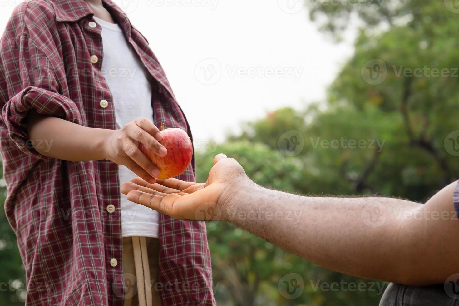 figlio dà una mela rossa a suo padre, un ragazzo afroamericano consegnò una mela a suo padre foto