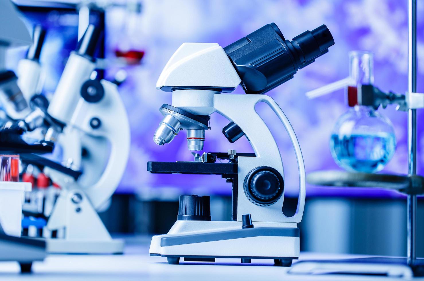 microscopio e laboratorio con attrezzatura per provette chimiche in laboratorio luci blu, scienza e concetto di esperimento foto