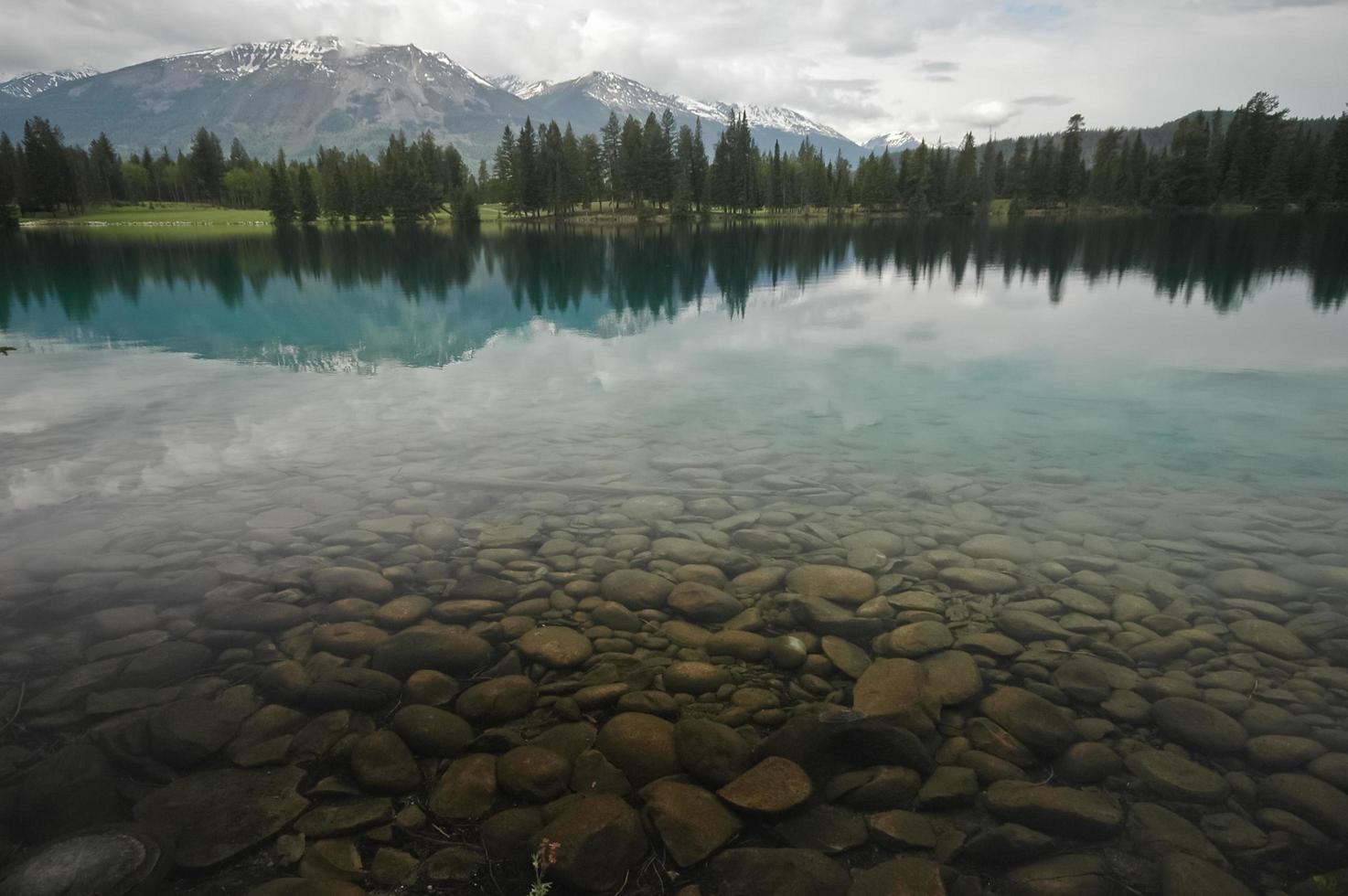 calmo lago limpido e catena montuosa innevata foto