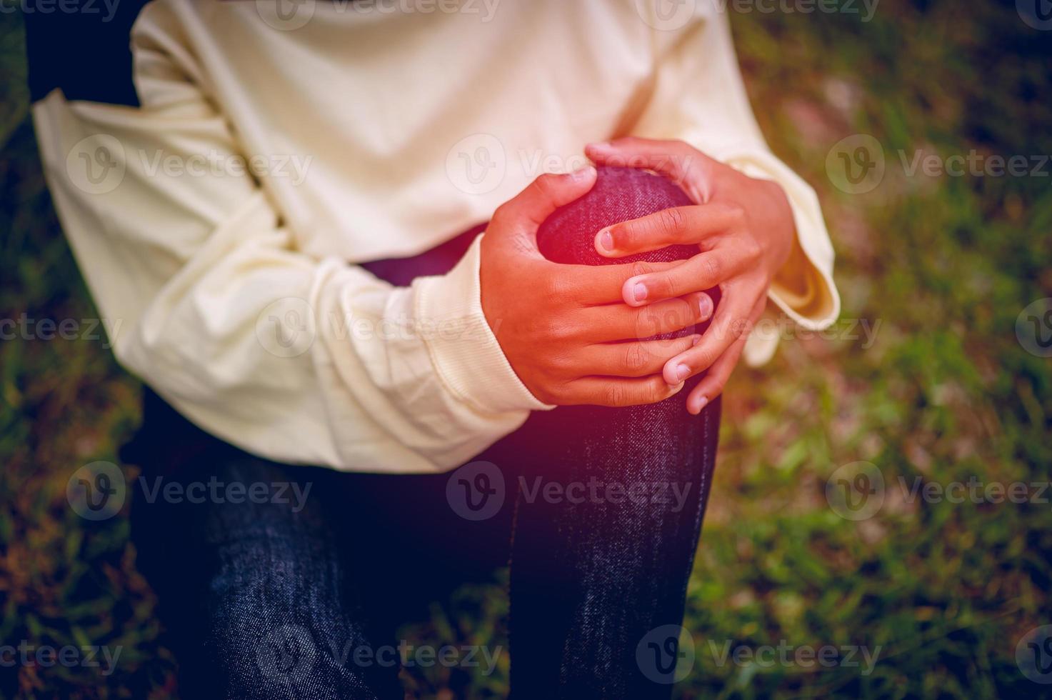 immagine di un giovane ragazzo seduto su un dolore al ginocchio, un concetto osseo foto