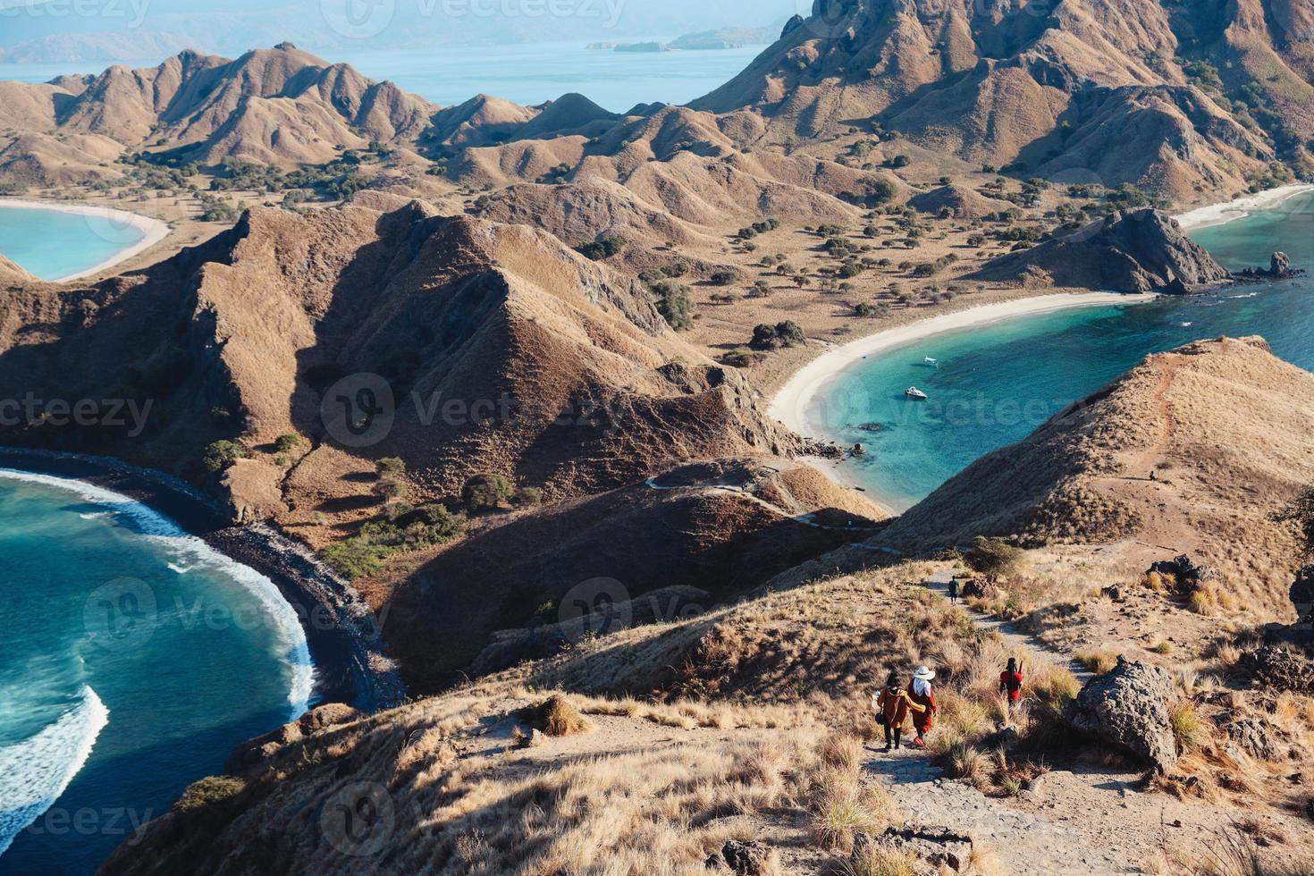 vista panoramica dalla cima dell'isola di padar a labuan bajo con turisti che camminano giù per la collina foto