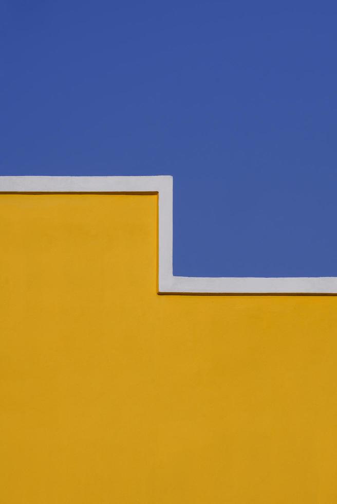 forma geometrica di muro di cemento giallo vuoto contro il cielo blu chiaro in cornice verticale per architettura e concetto di design di sfondo foto