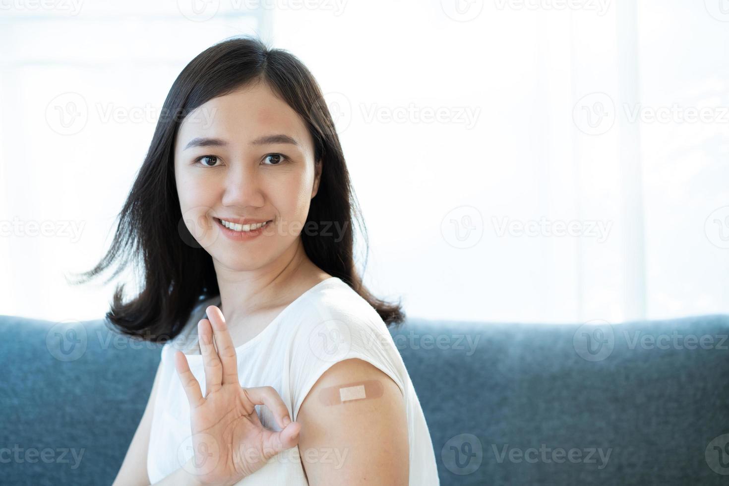 giovane donna asiatica che mostra un punto di vaccinazione sul braccio. foto