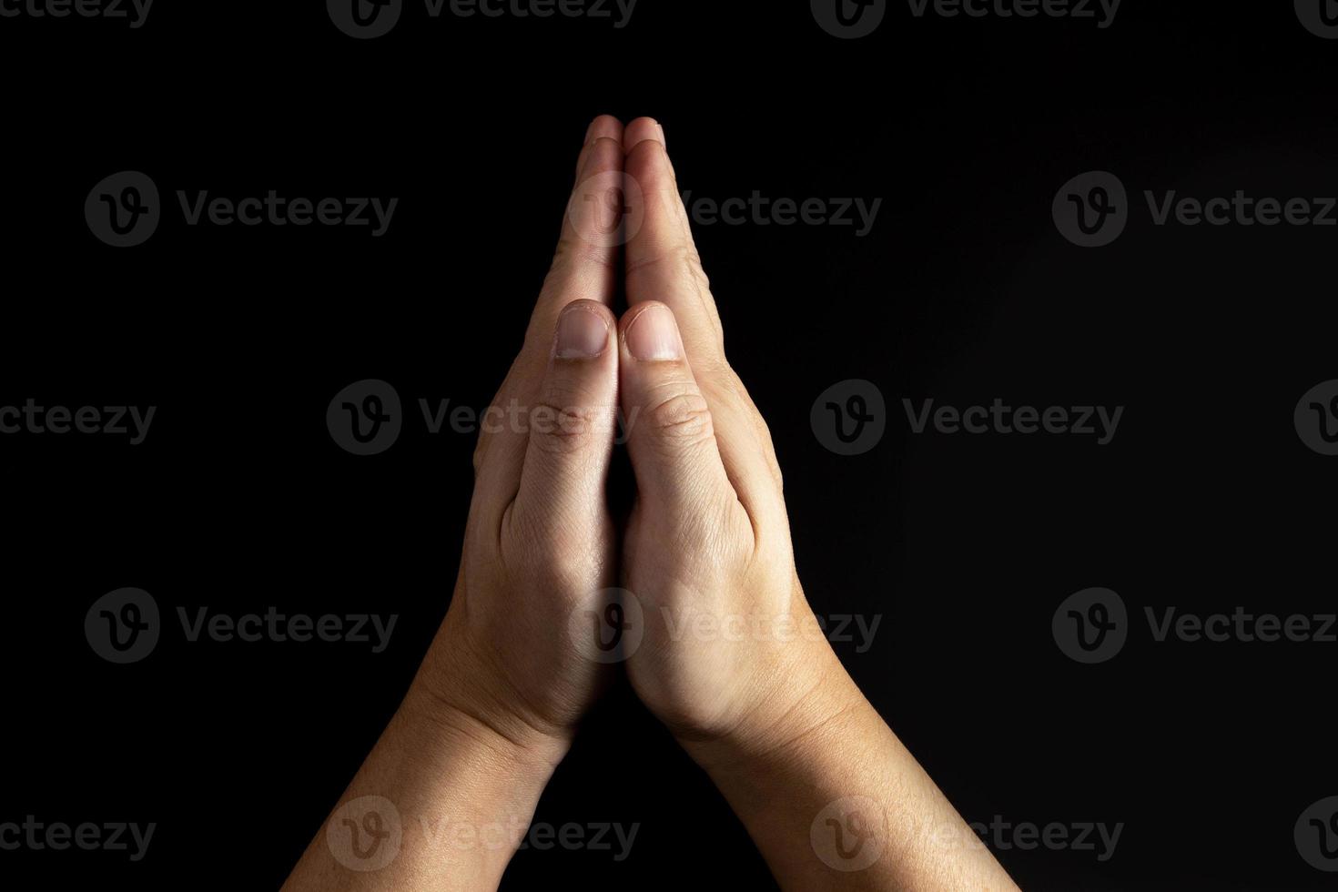 l'uomo la cui mano sta pregando sullo sfondo nero foto