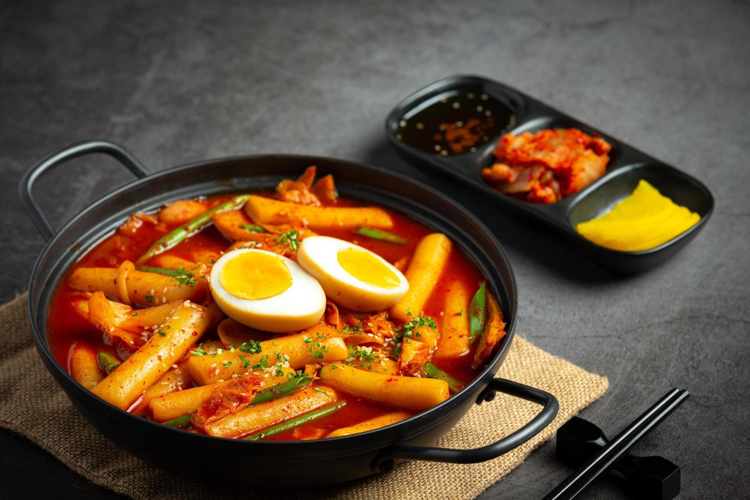 cibo tradizionale coreano tokbokki di formaggio su sfondo nero. piatto da pranzo. foto