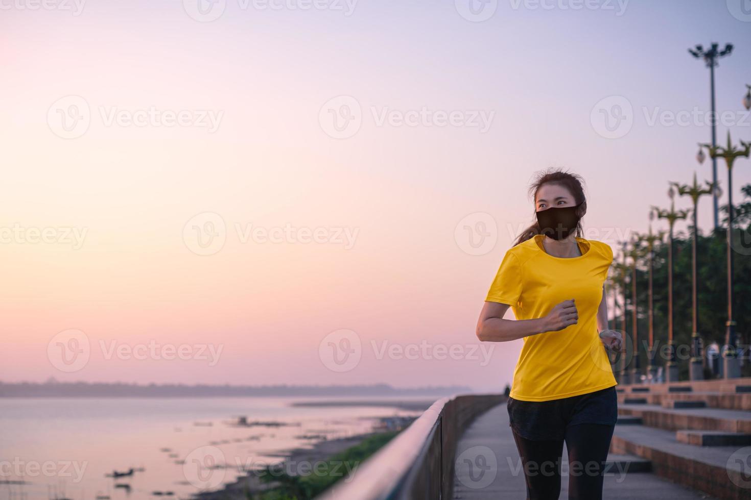 donna asiatica che corre e si esercita indossando una maschera protettiva covid-19 un allenamento all'aperto sul lungofiume al mattino. foto